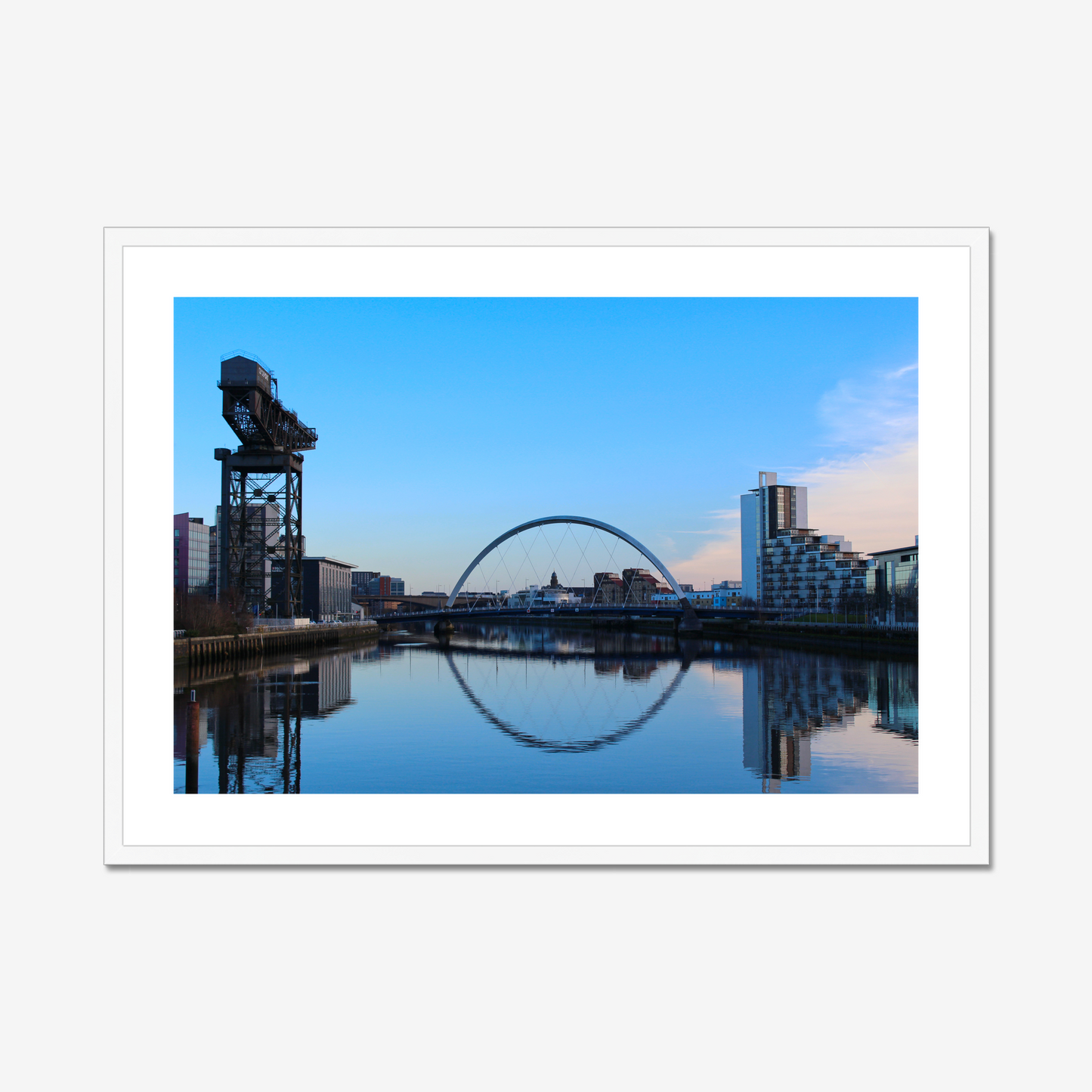 Cityscape with a bridge and modern buildings reflected in water, framed picture.