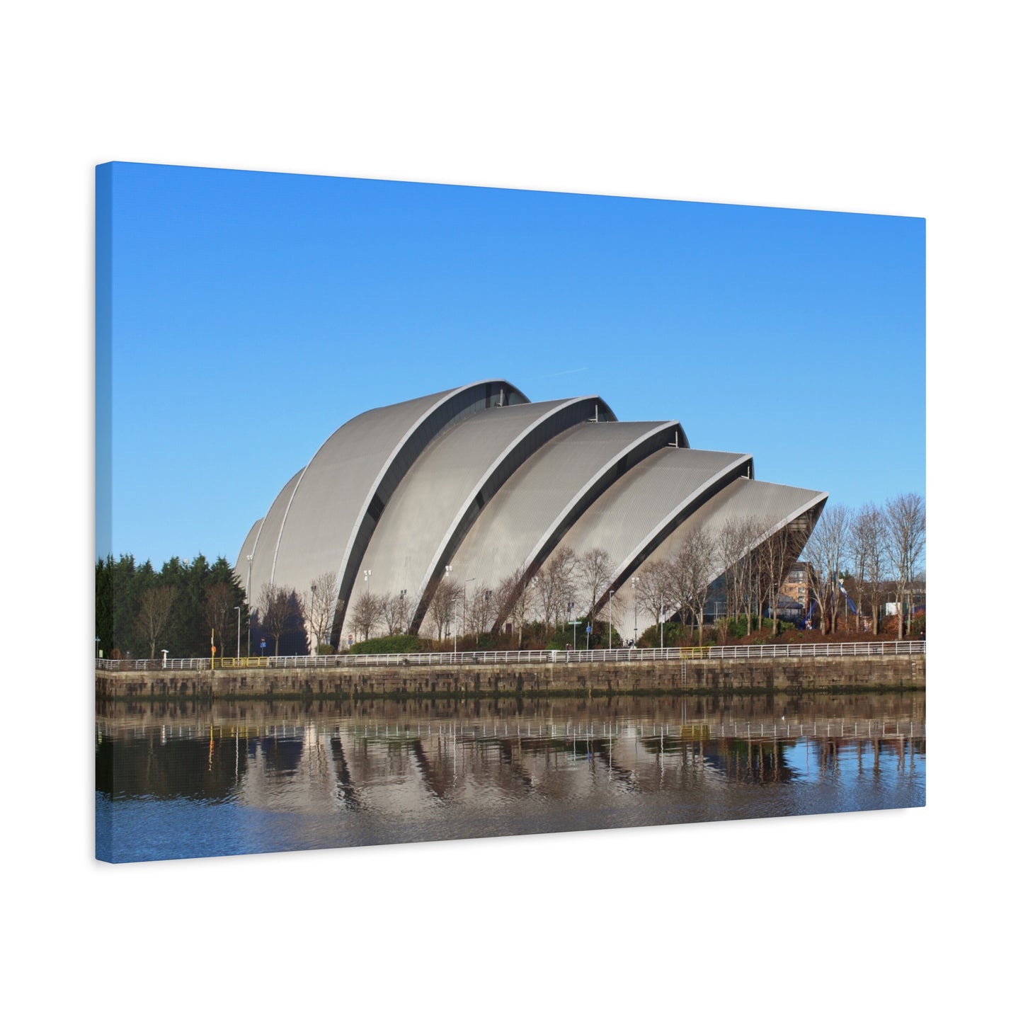 Modern architectural building with curved design reflected in water, against a clear blue sky.