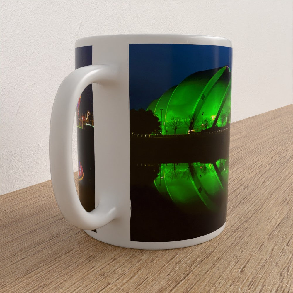White mug with a green bottle and cityscape design on a wooden surface