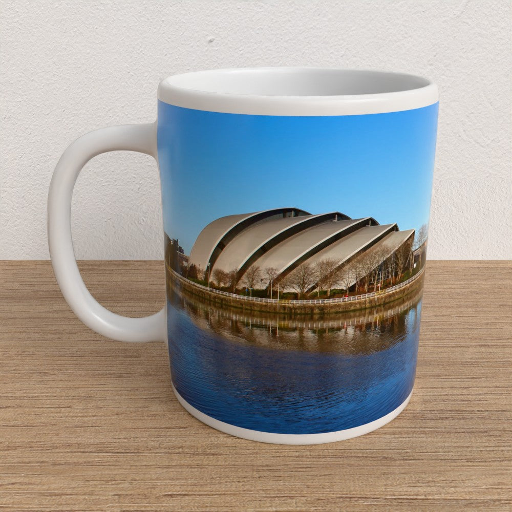 Mug with a scenic design of a building and water on a wooden surface