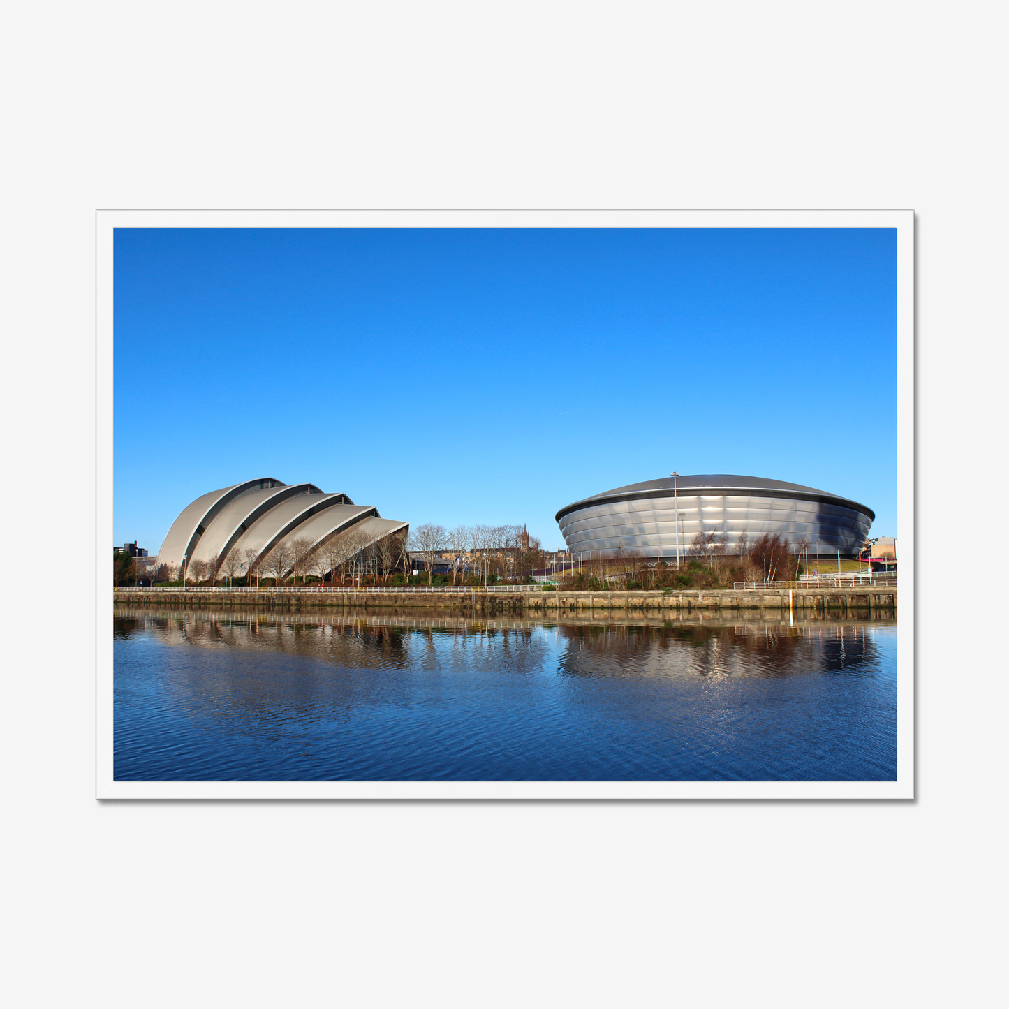 Framed photograph of modern architectural buildings reflected in water with a clear blue sky