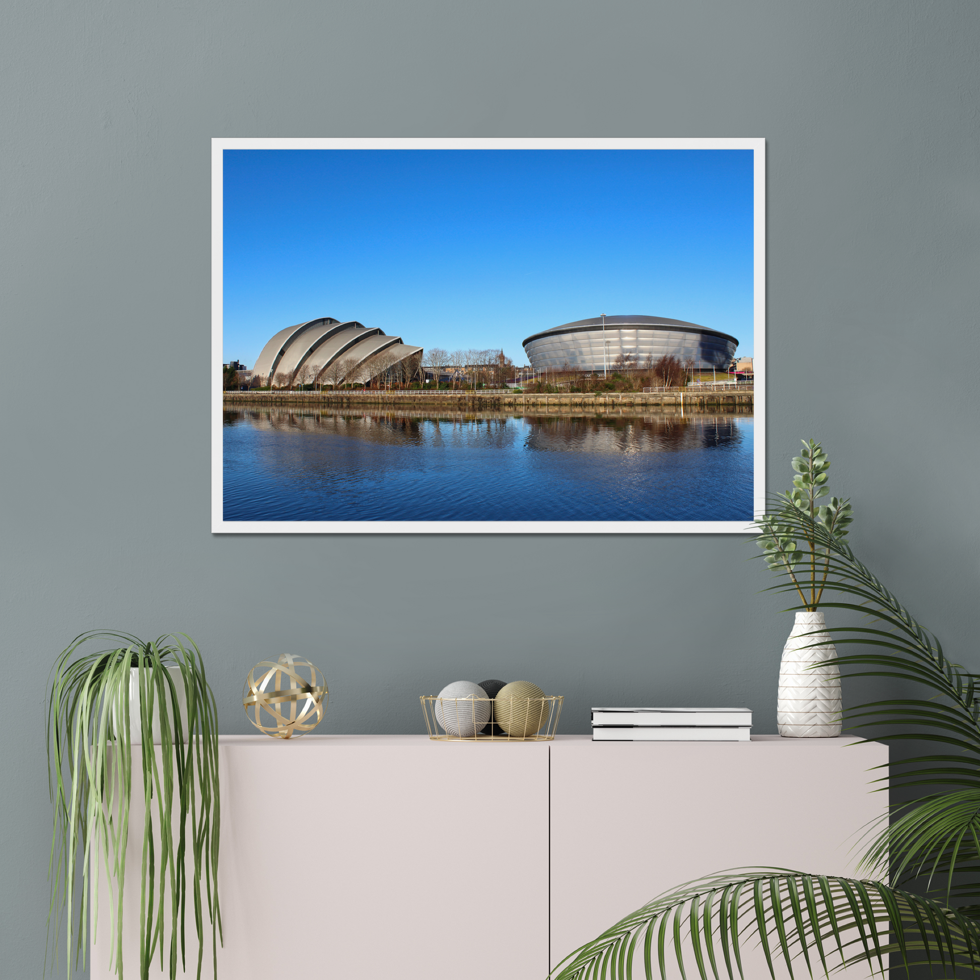 Framed photograph of modern architectural buildings reflected in water with a clear blue sky