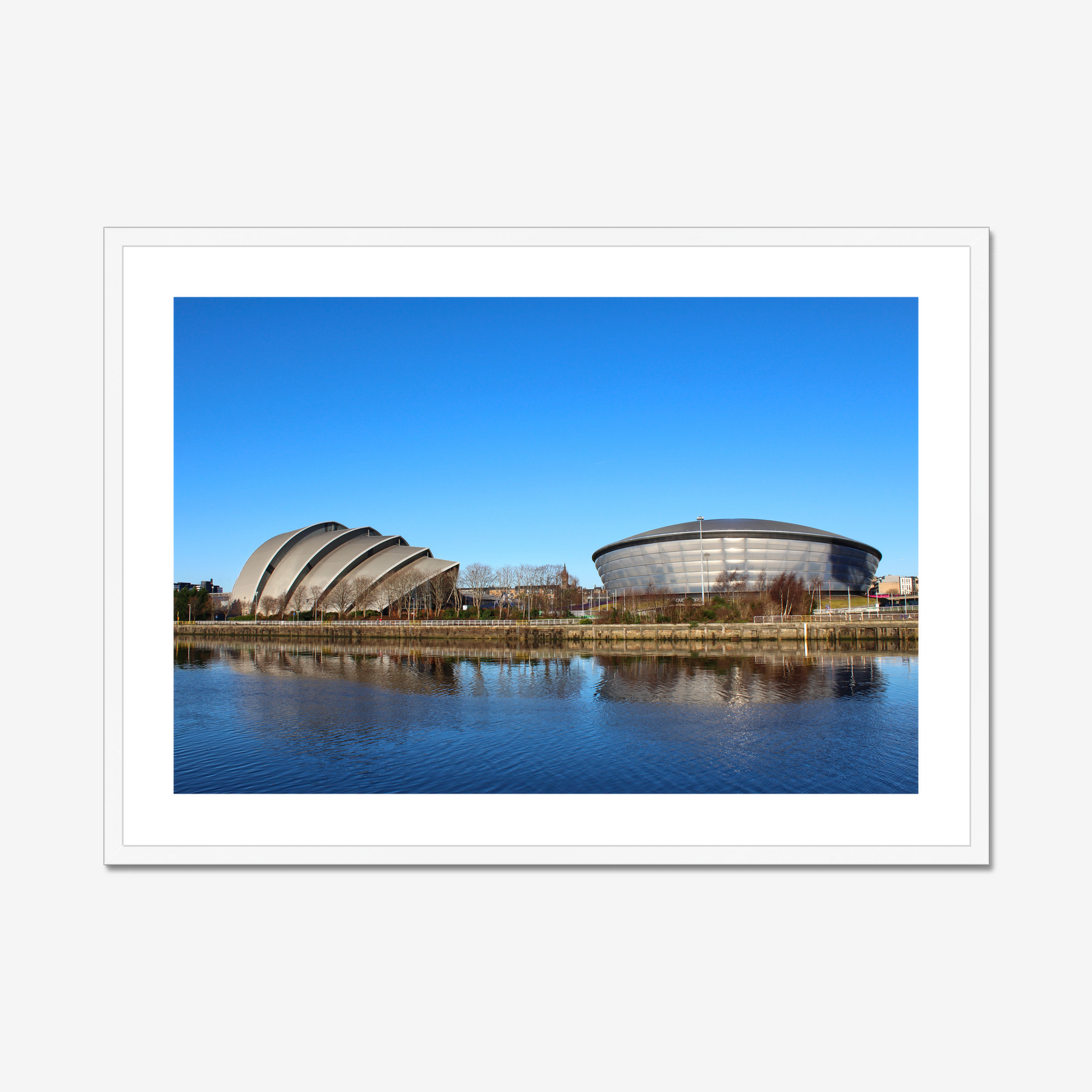 Framed photograph of modern architectural buildings reflected in water with a clear blue sky