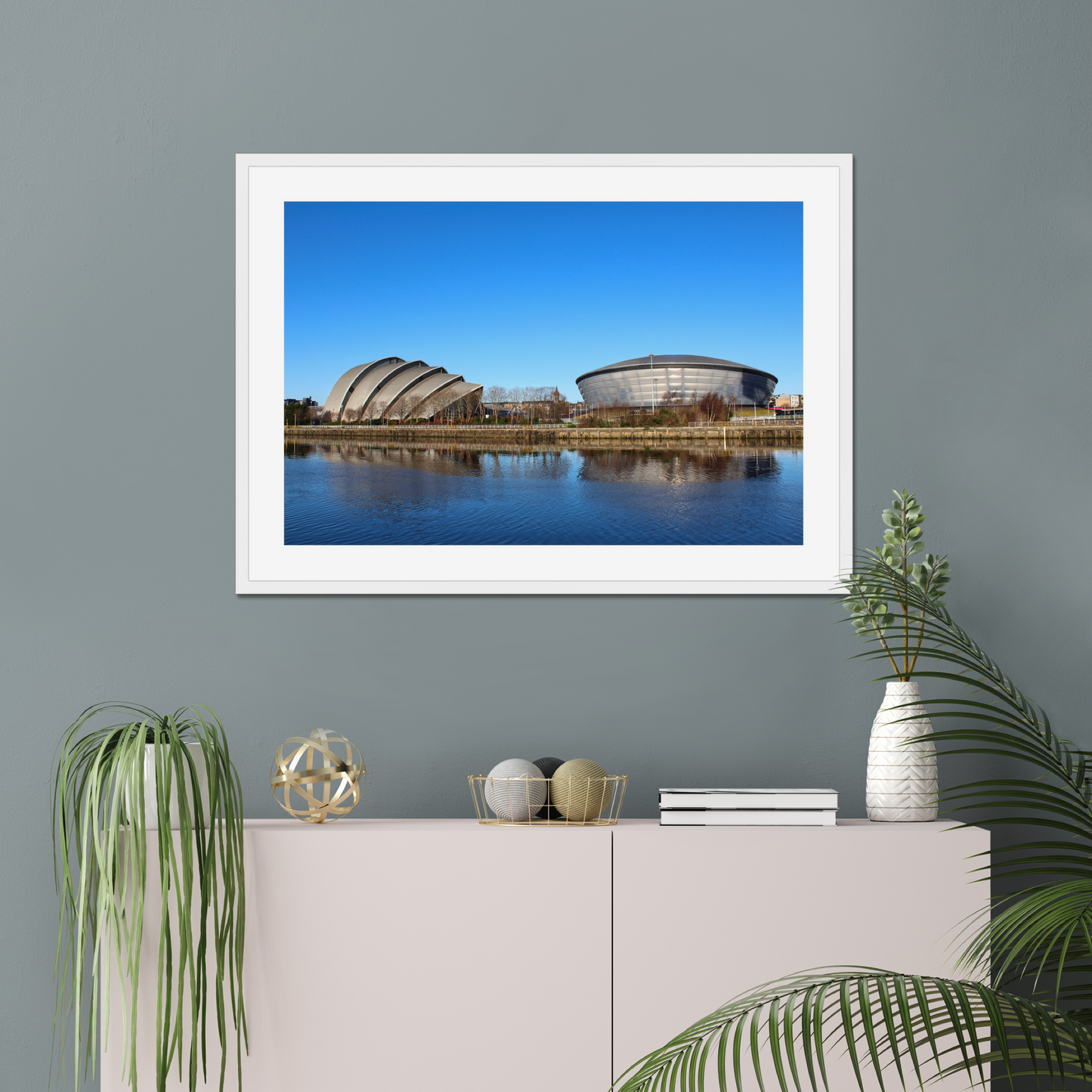 Framed photograph of modern architectural buildings reflected in water with a clear blue sky