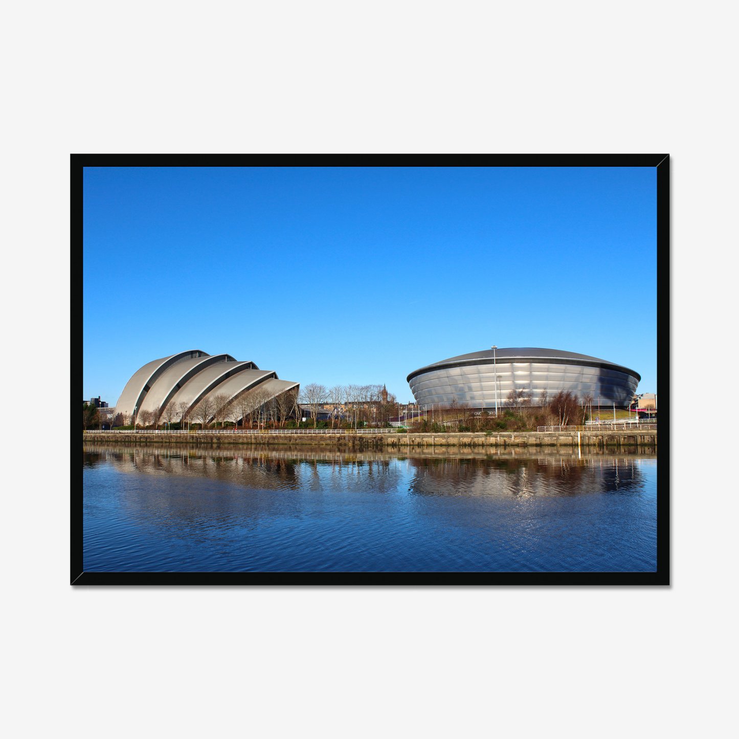 Framed photograph of modern architectural buildings reflected in water with a clear blue sky