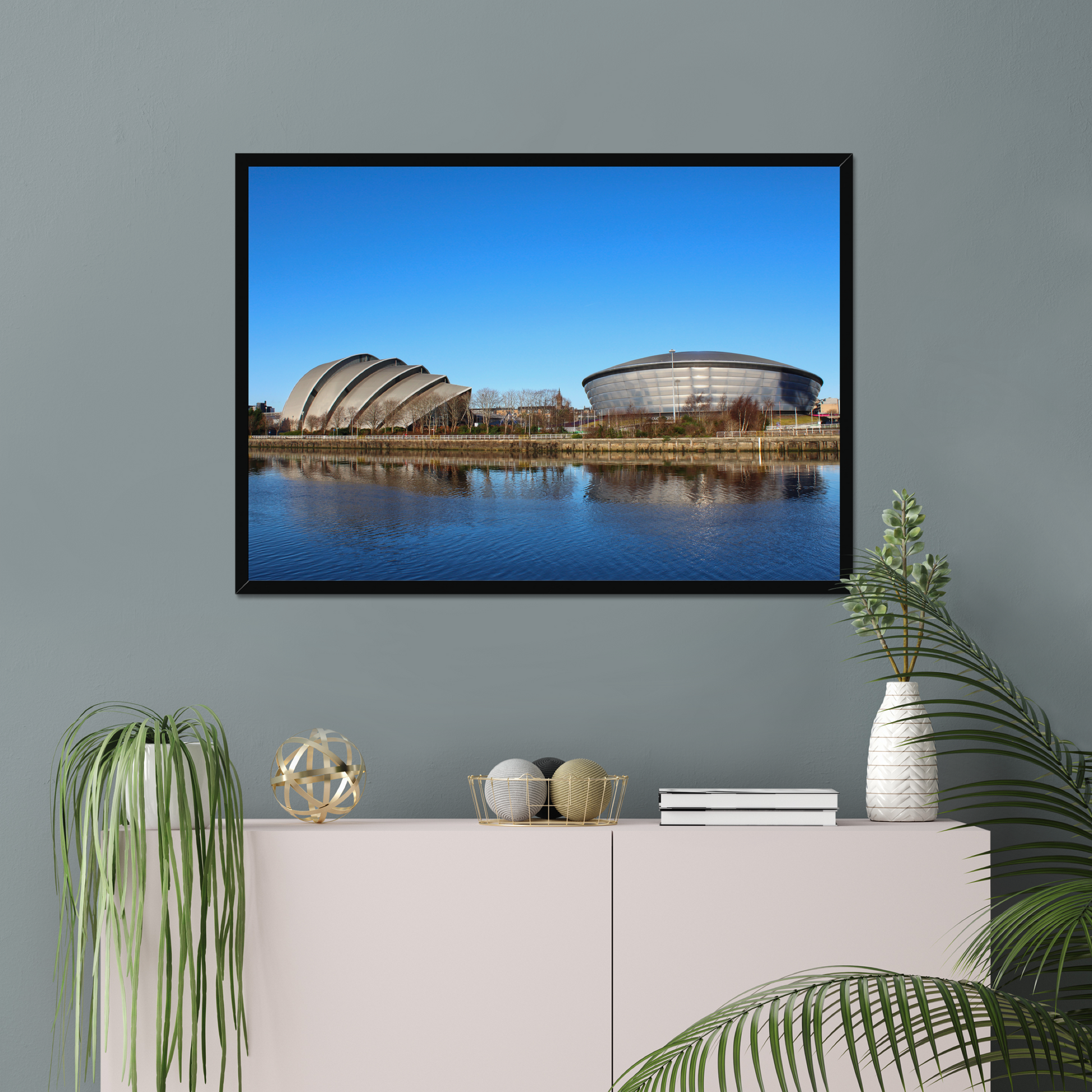 Framed photograph of modern architectural buildings reflected in water with a clear blue sky