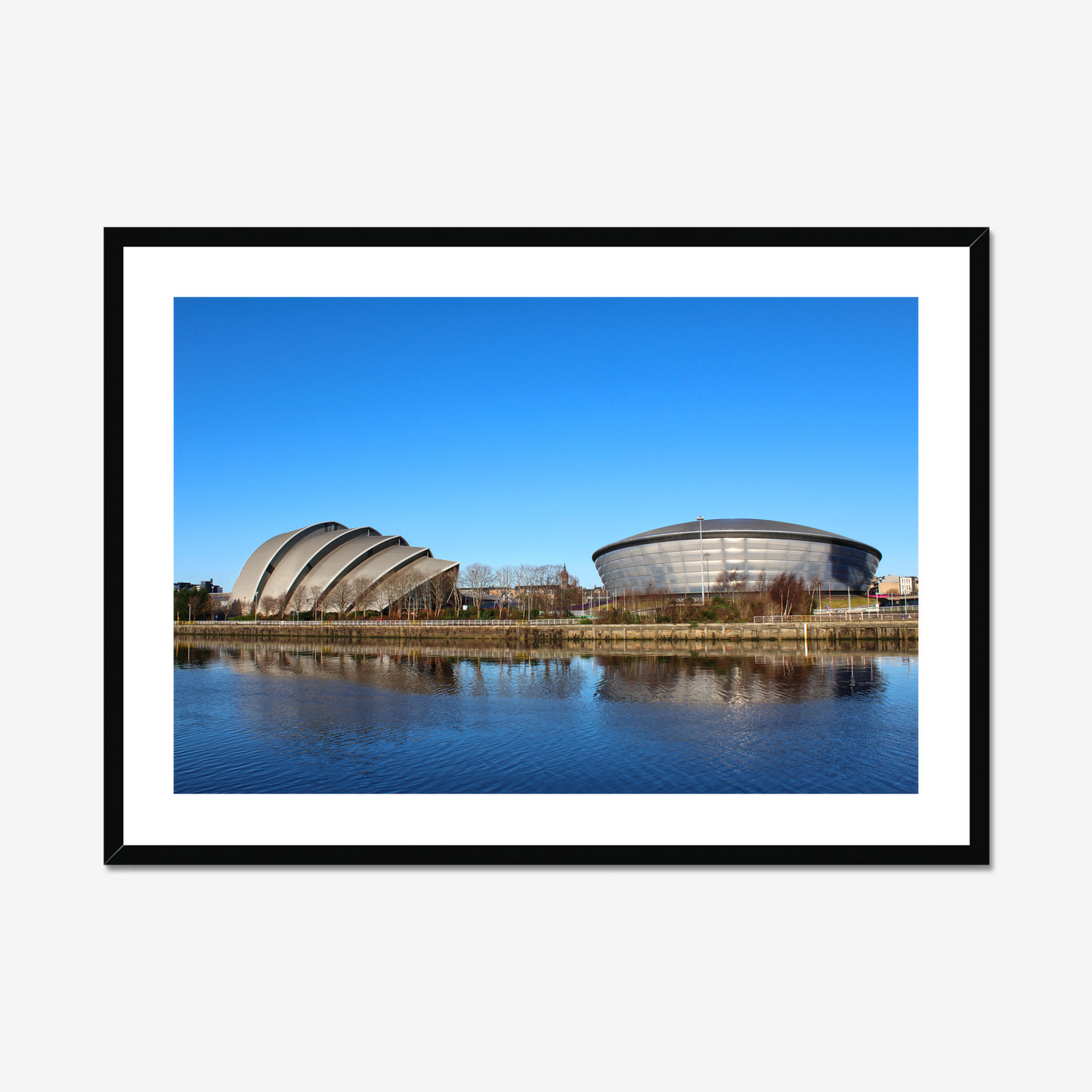 Framed photograph of modern architectural buildings reflected in water with a clear blue sky