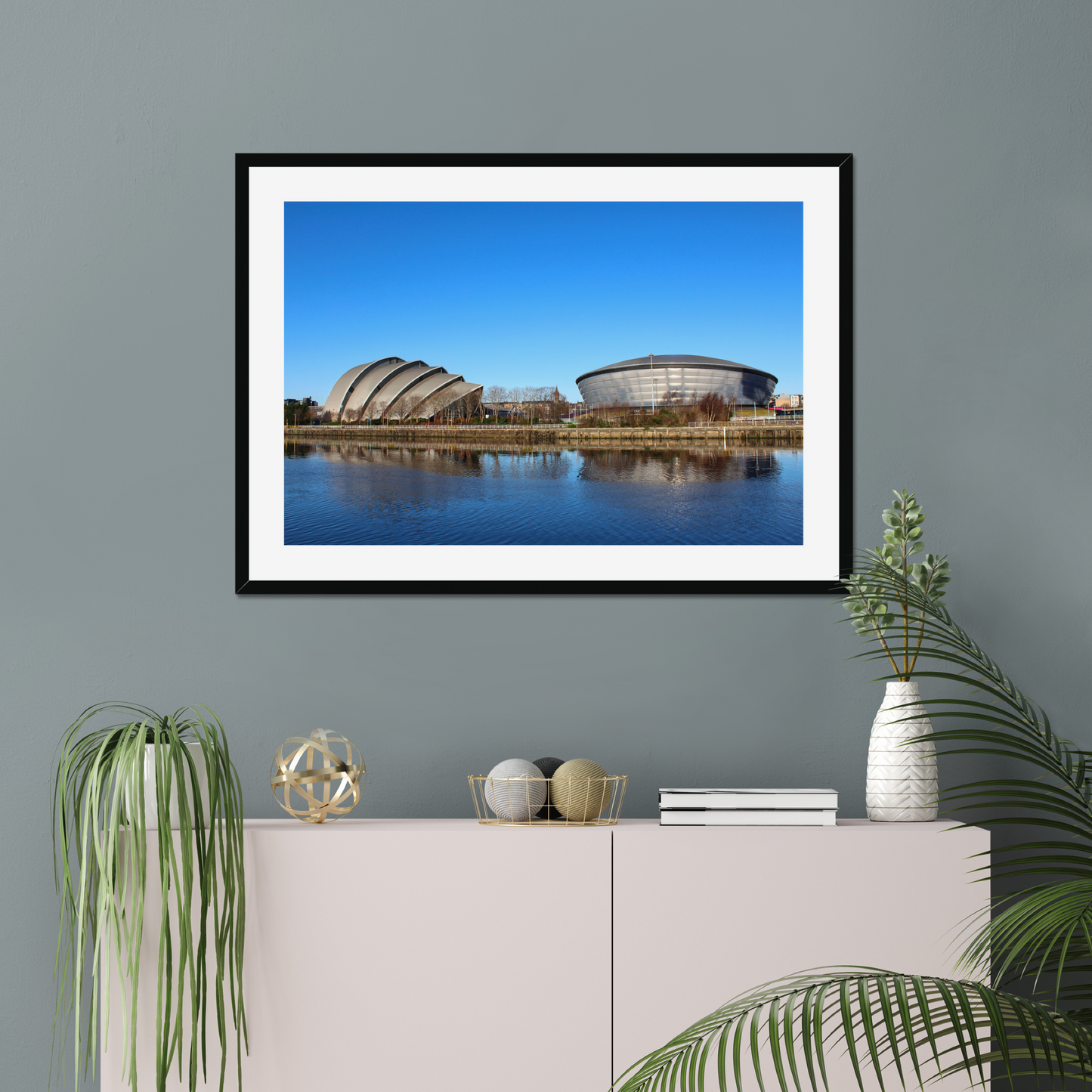 Framed photograph of modern architectural buildings reflected in water with a clear blue sky