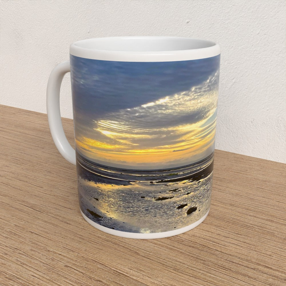 Mug with a sunset over water design on a wooden surface