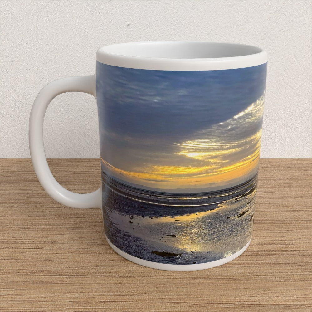 Mug with a sunset over water design on a wooden surface