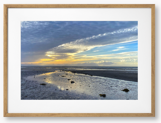 Framed Photo Of A Sunset over a beach with clouds and water reflections