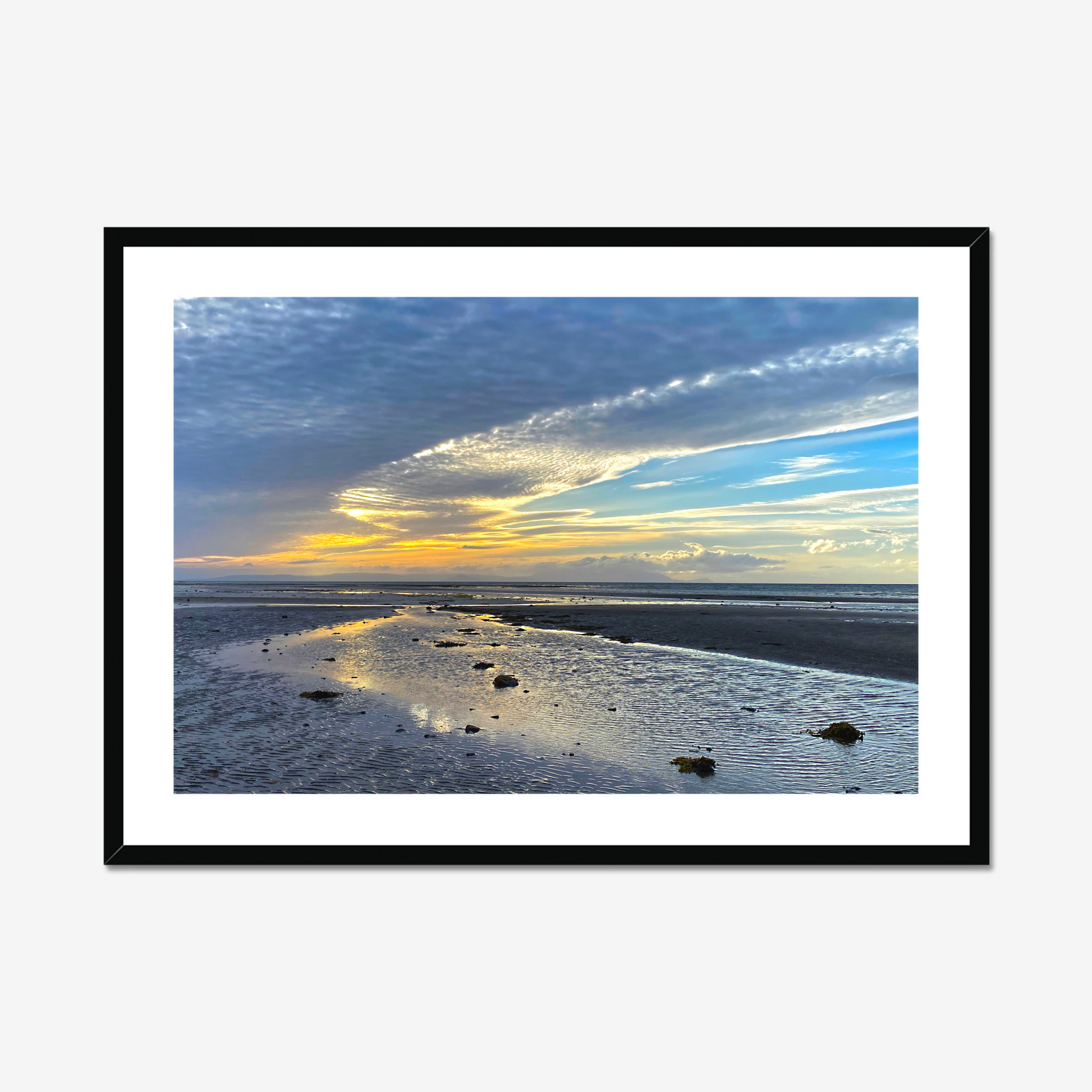 Framed photograph of a sunset over a beach with clouds and water reflections