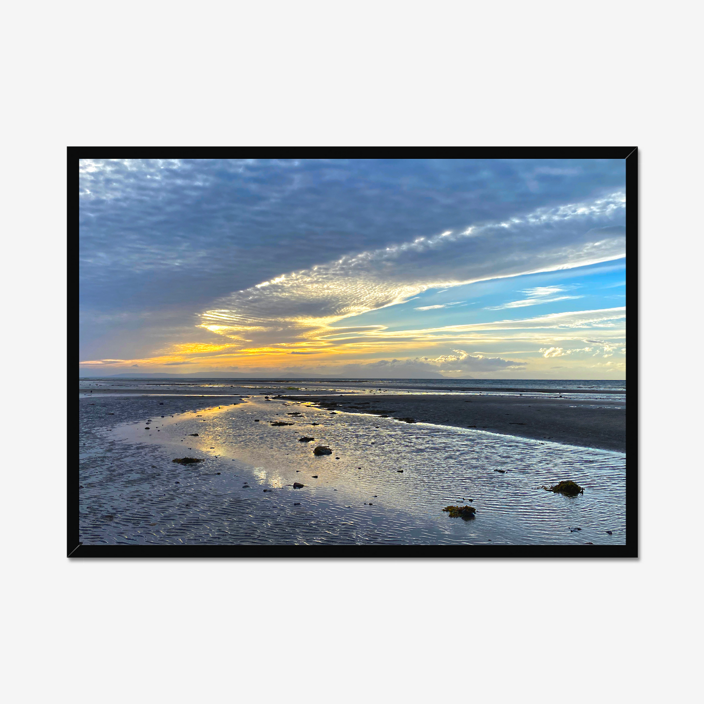 Framed photograph of a sunset over a beach with clouds and water reflections