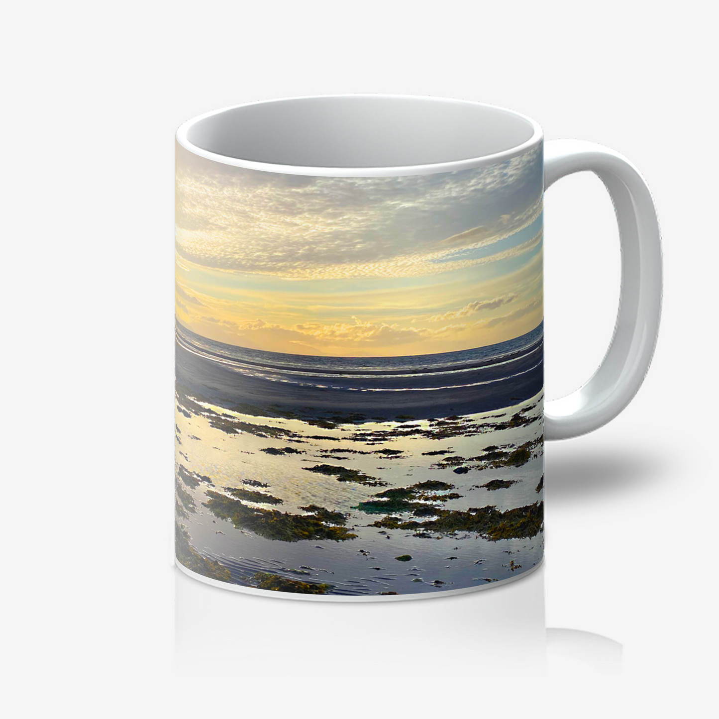 Mug with a scenic design of a sunset over water on a white background