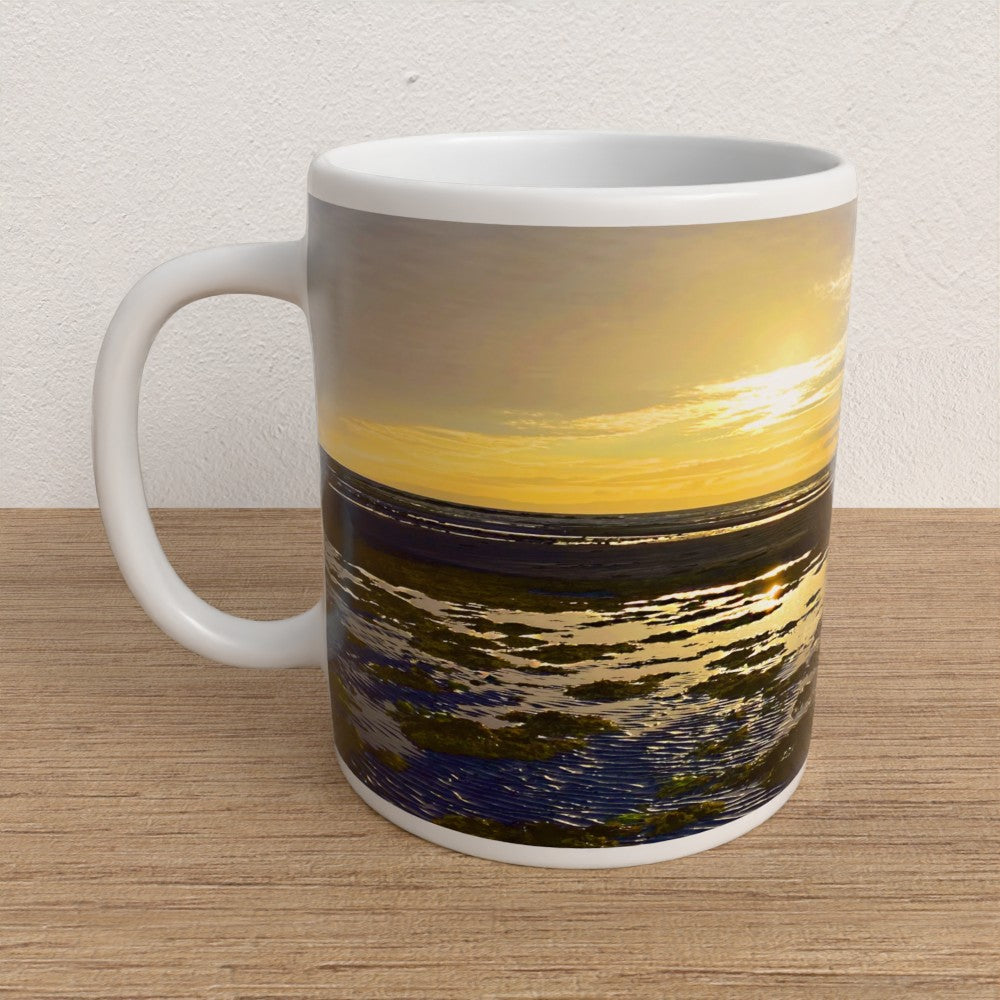Mug with a scenic design of water and sky on a wooden surface