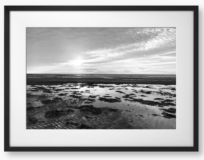 Black and white framed photograph of a coastal landscape with a sunset.