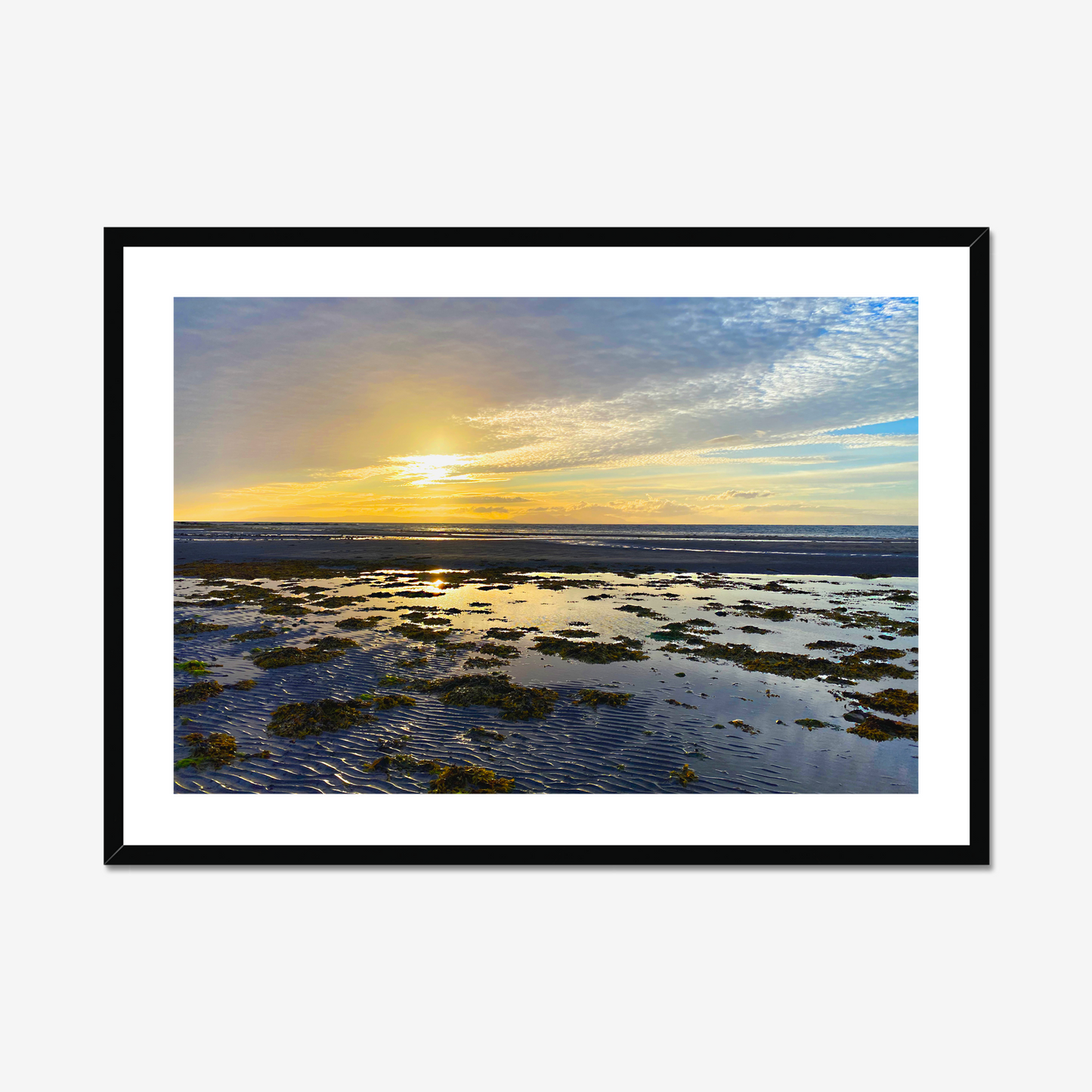 Framed photograph of a sunset over a coastal landscape with a black frame.