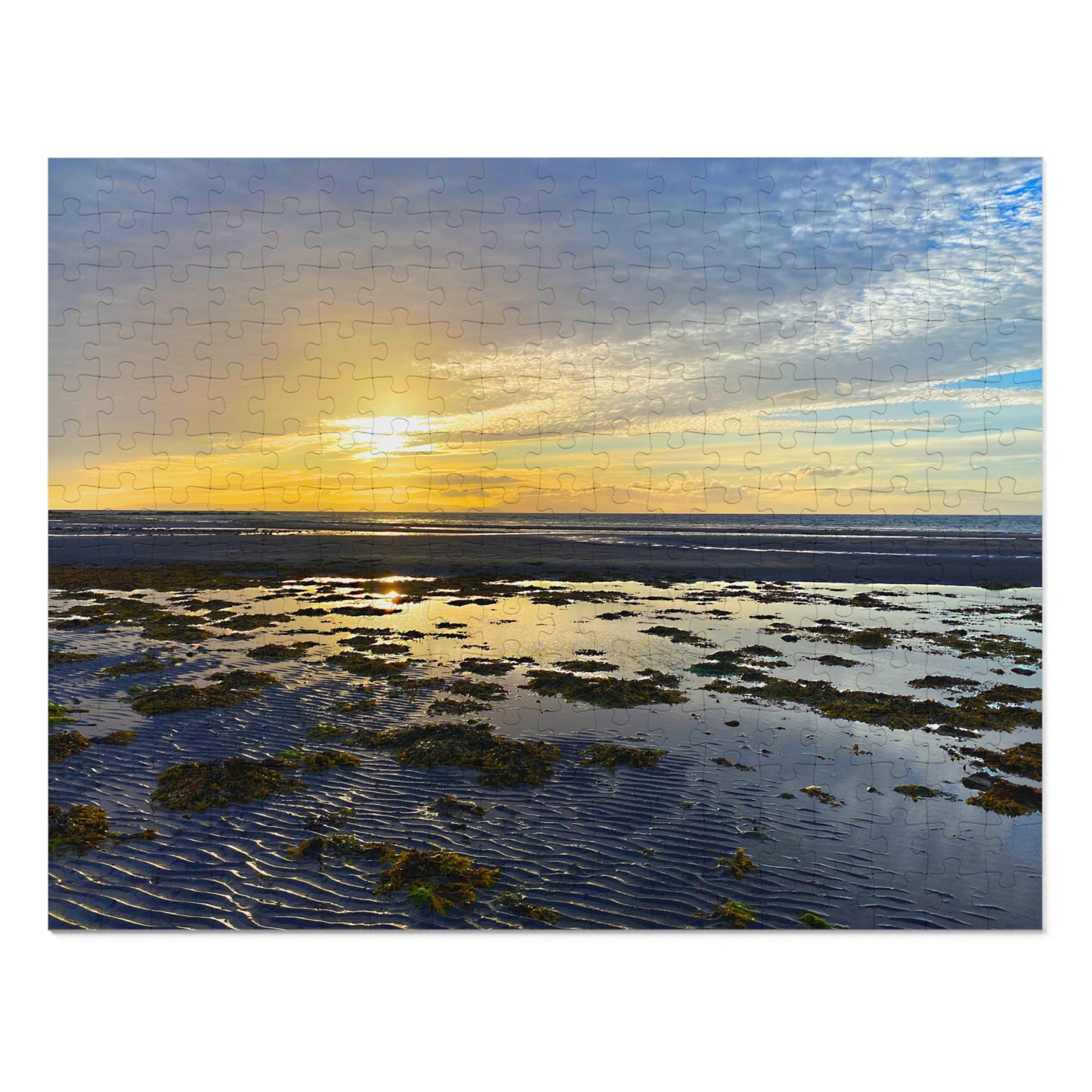 Sunset over a coastal landscape with rocks and water, displayed on a puzzle.