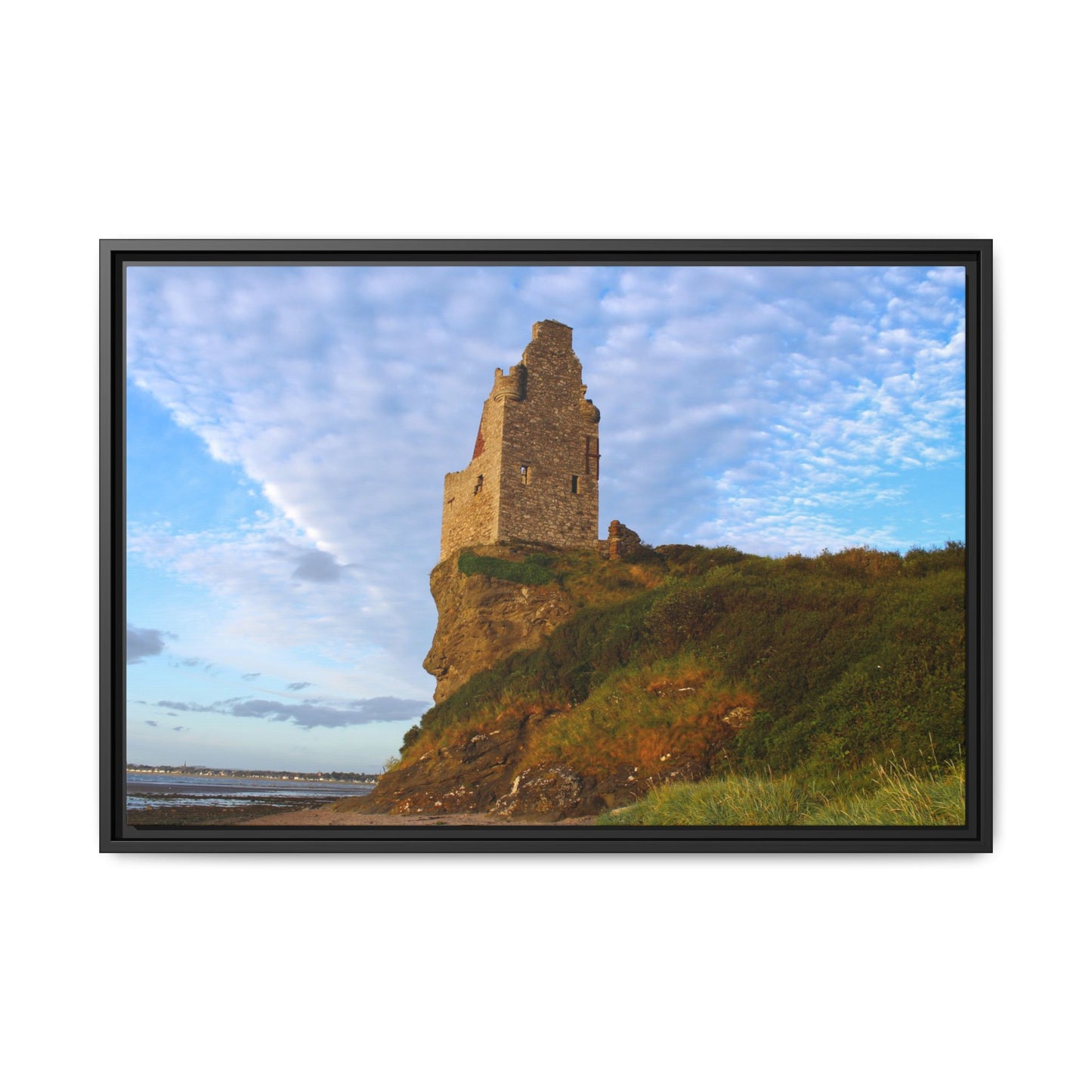 Framed photograph of a stone tower on a cliff with a blue sky.