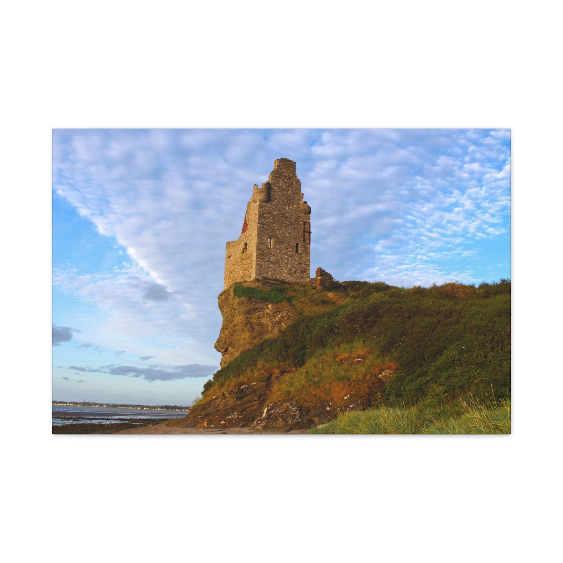 Ruins of a tower on a cliff with a blue sky and clouds in the background
