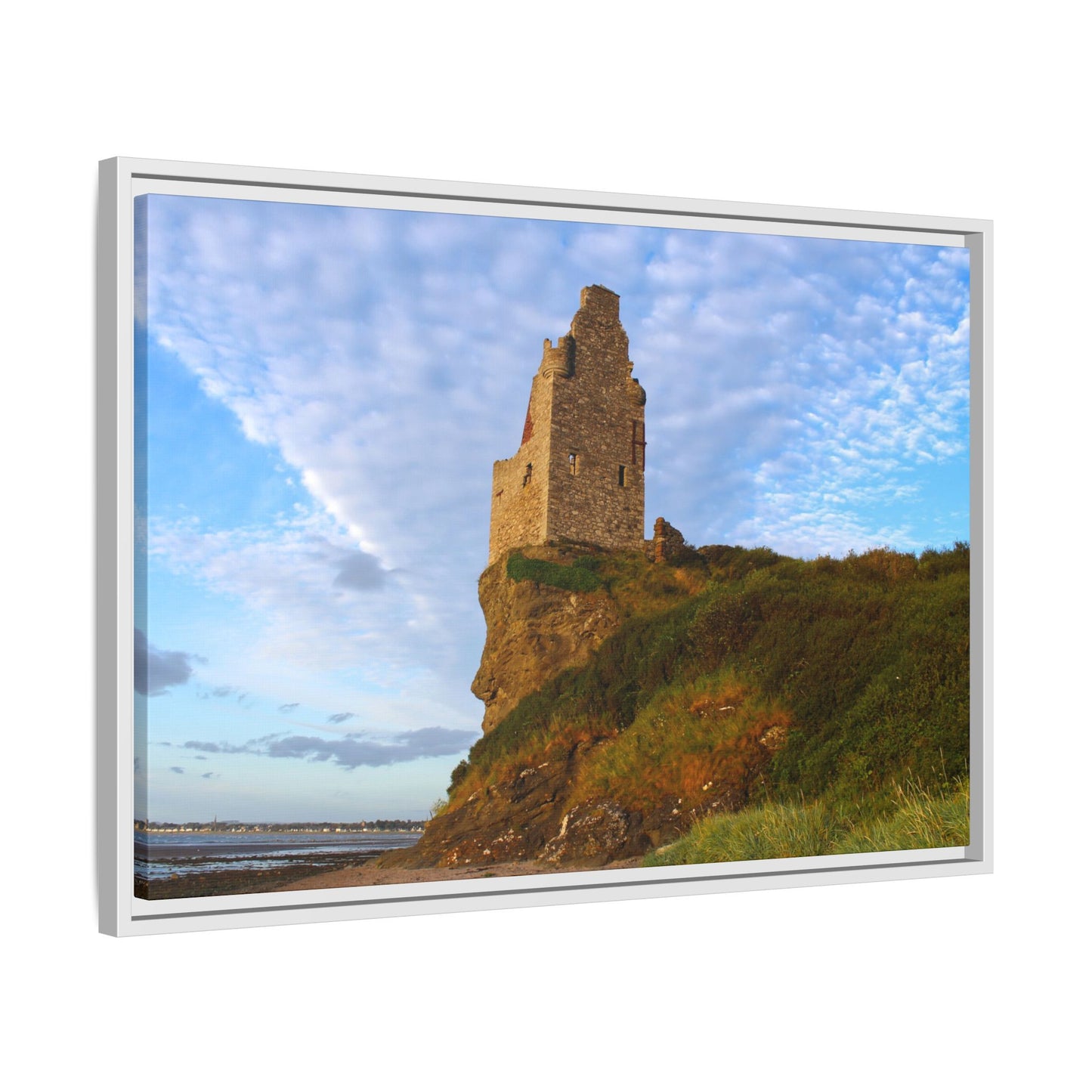 Ruins of a tower on a cliff with a blue sky and clouds.