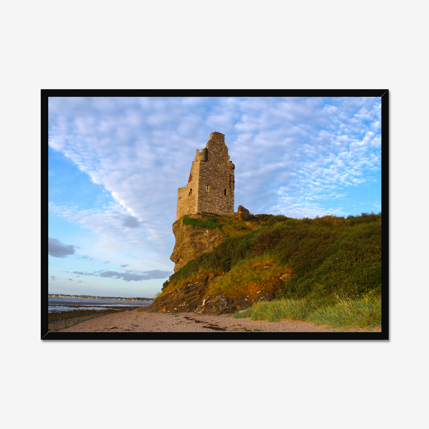 Ruined tower on a cliff with a blue sky and clouds