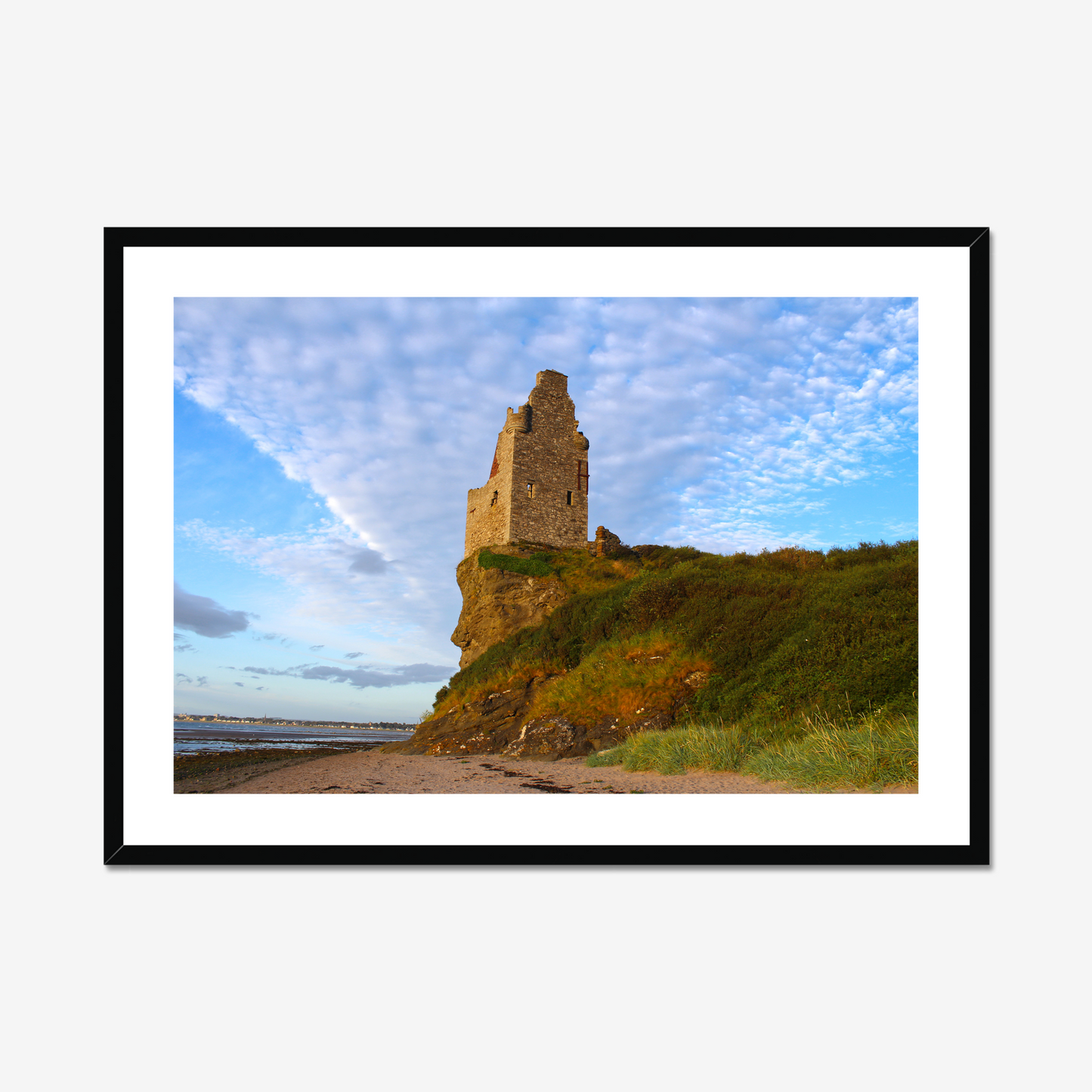 Ruined tower on a cliff with a blue sky and clouds