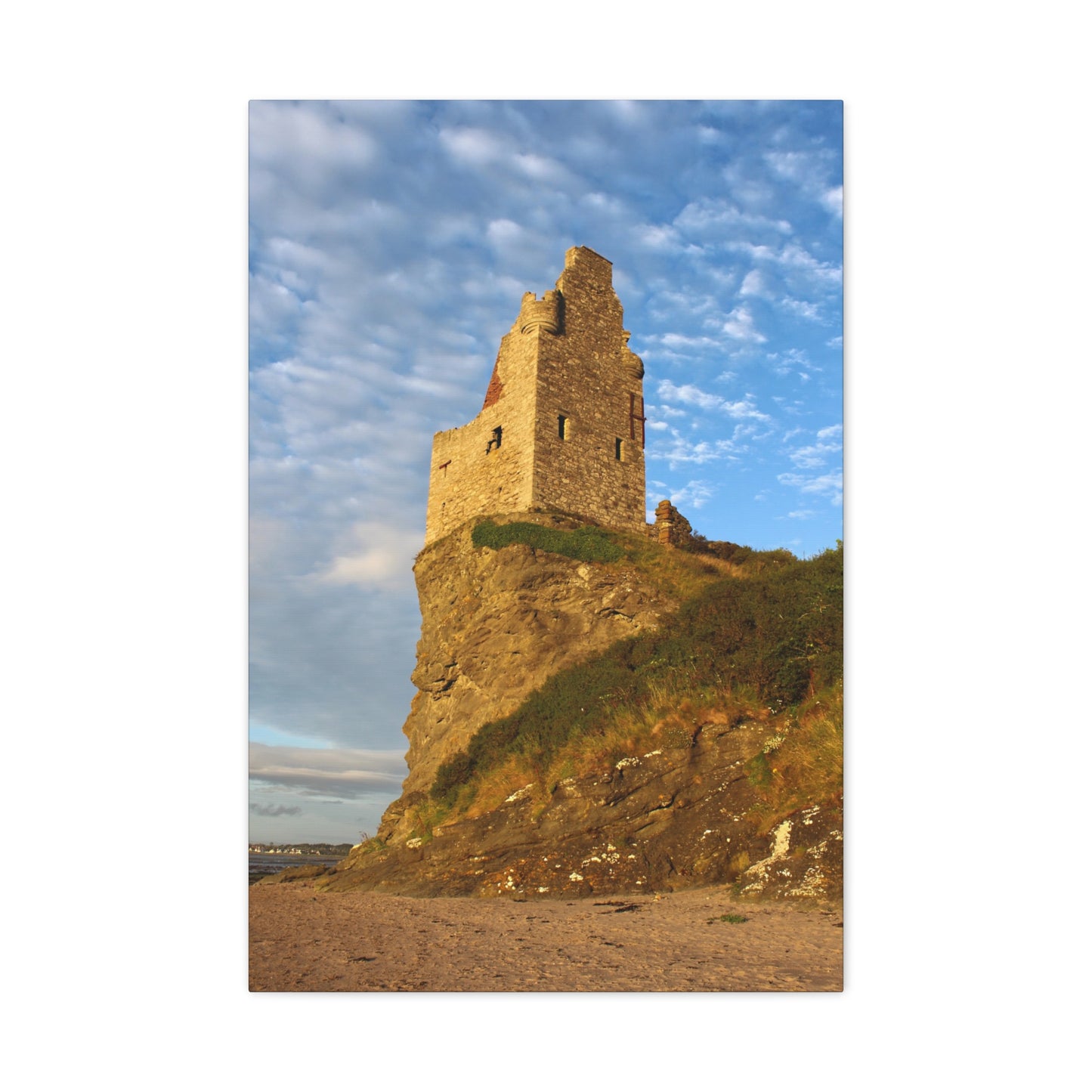 Ruins of a tower on a cliff with a blue sky and clouds in the background