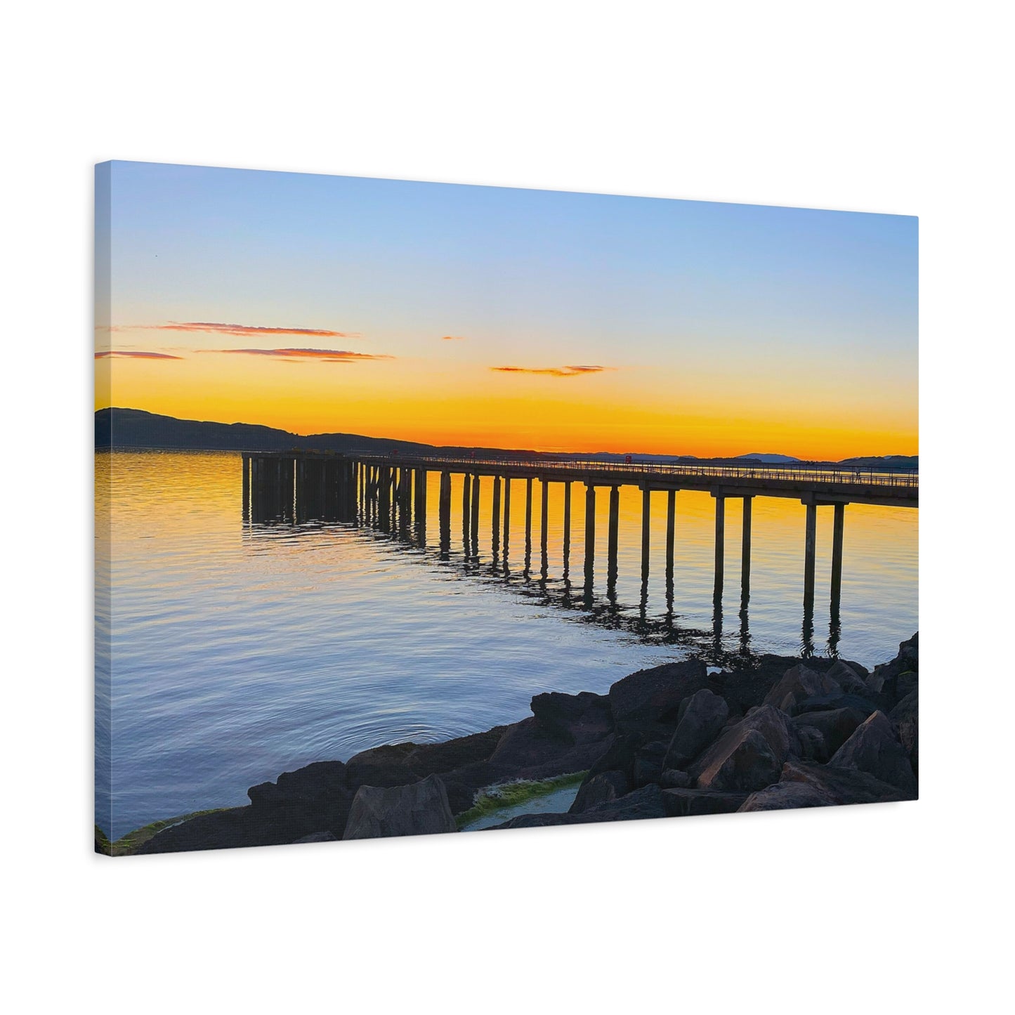 Canvas print of a sunset over a dock reflected in water with mountains in the background.