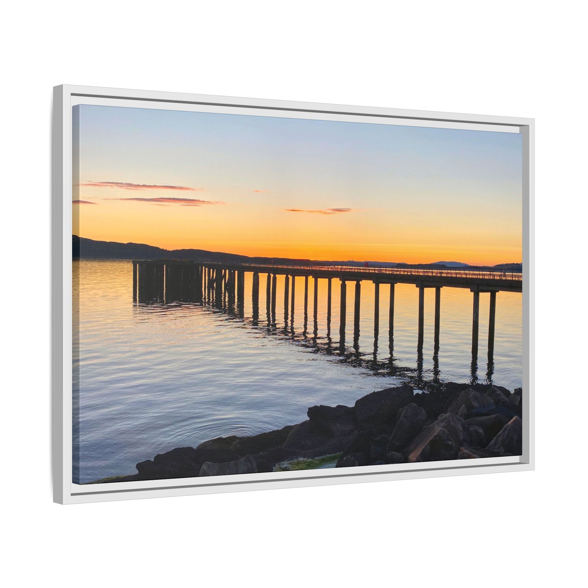 Framed artwork of a sunset over a pier with water reflections.
