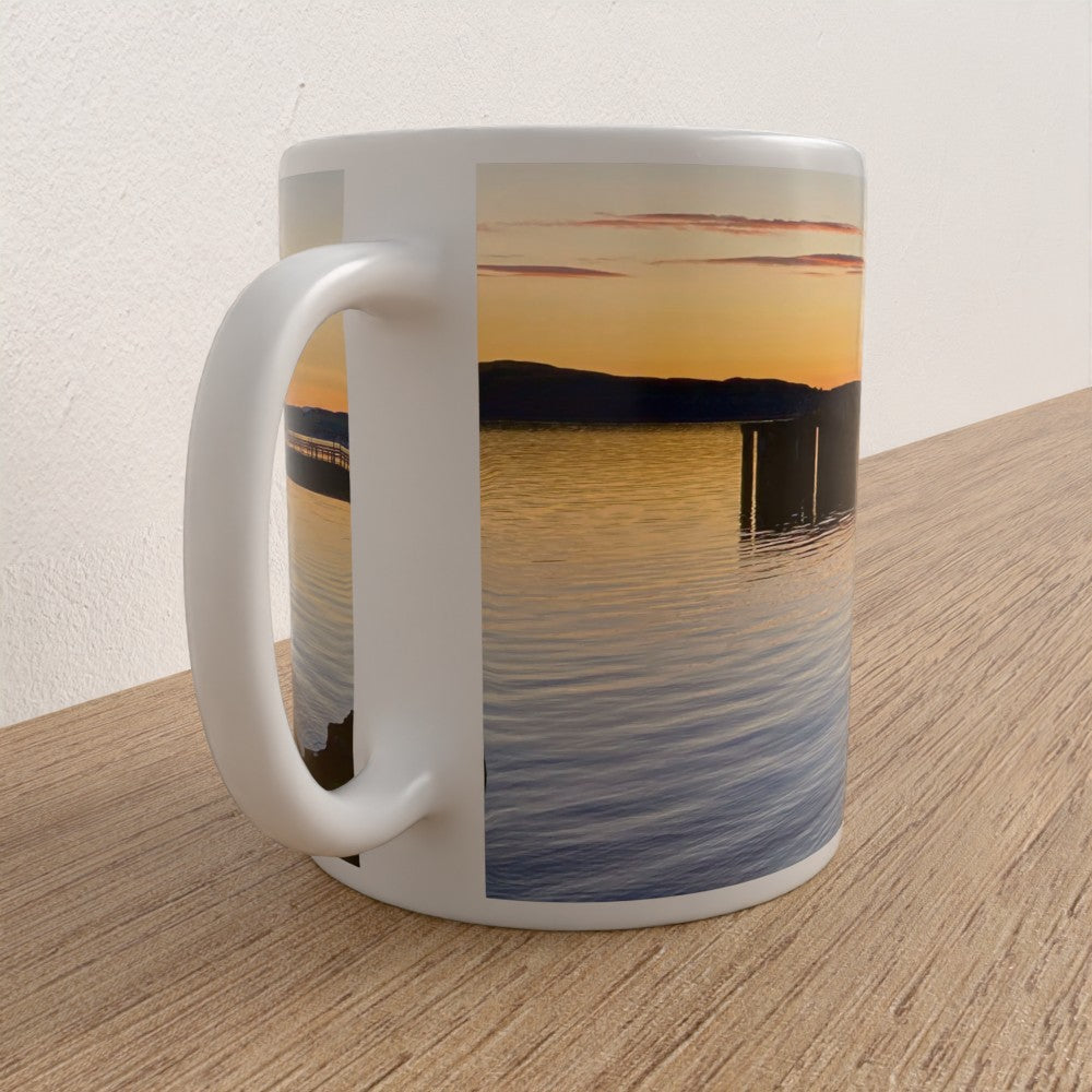 Mug with a sunset over water design on a wooden surface