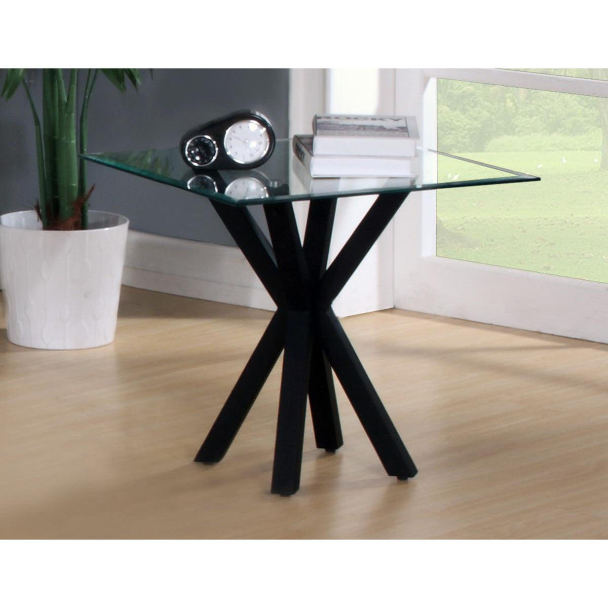 A black high gloss lamp table with a clear glass top, pictured in a room setting with decorative items on top.