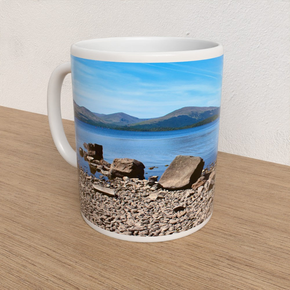 Mug with a scenic design of mountains and water on a wooden surface