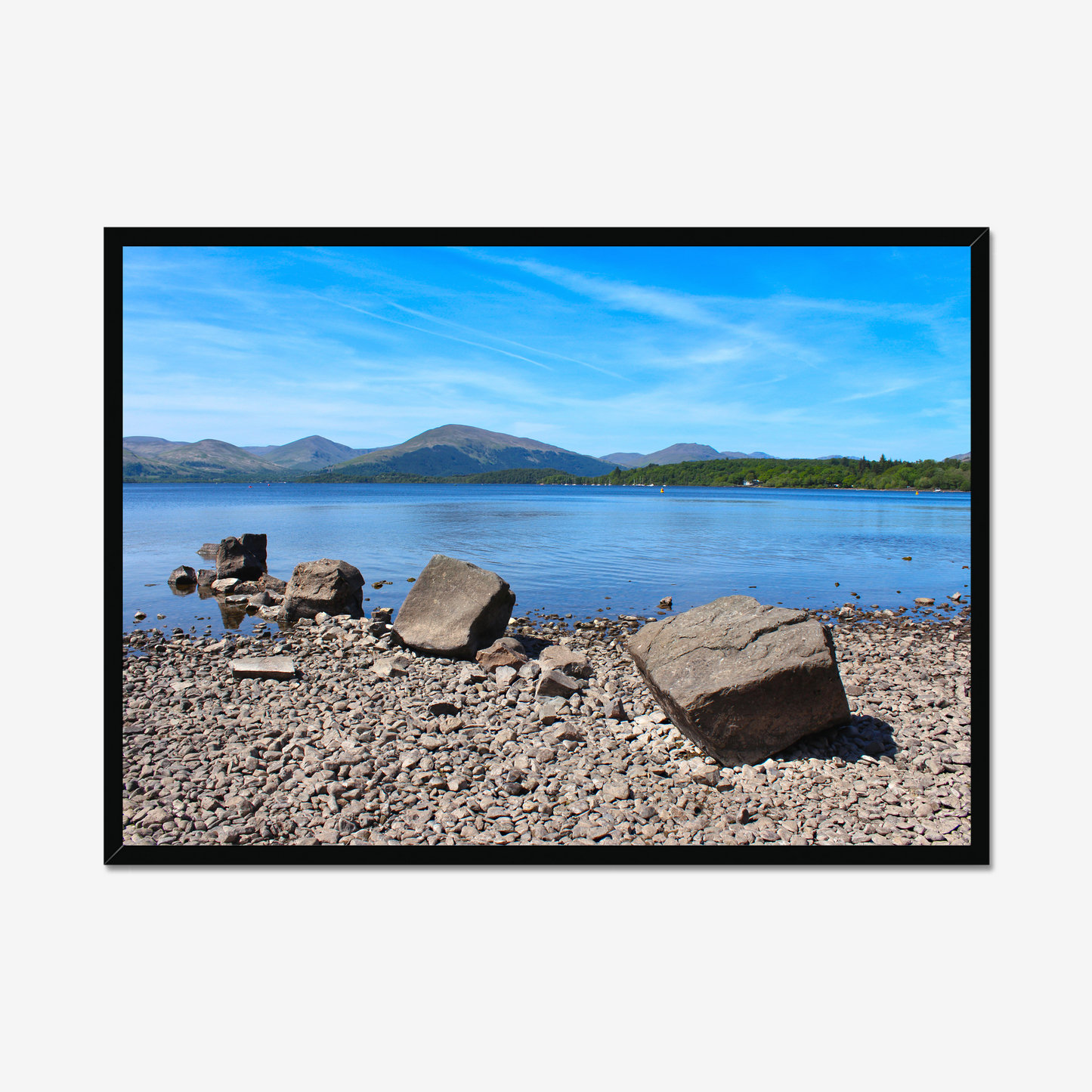 Framed photograph of a rocky shoreline with a lake and mountains in the background.