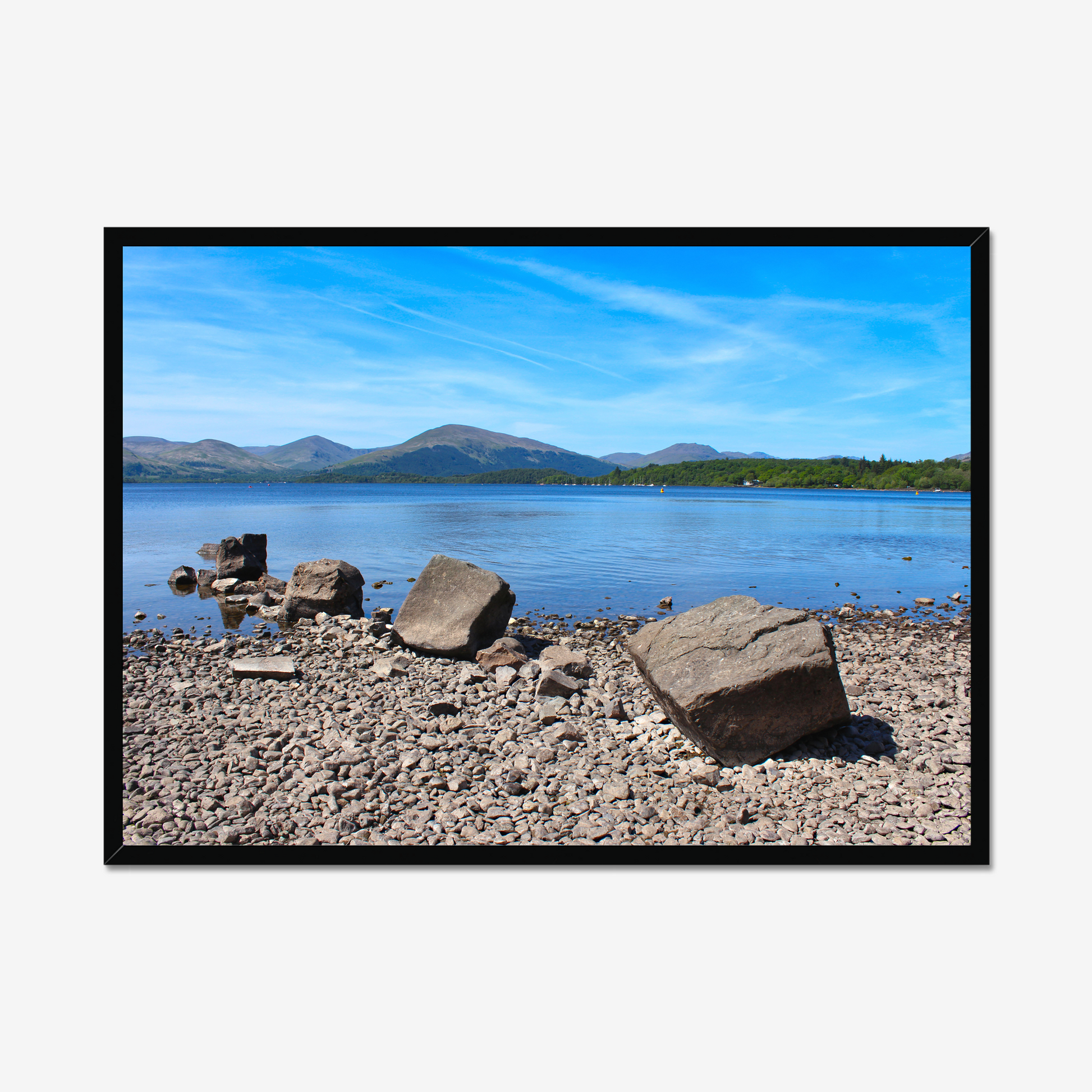 Framed photograph of a rocky shoreline with a lake and mountains in the background.