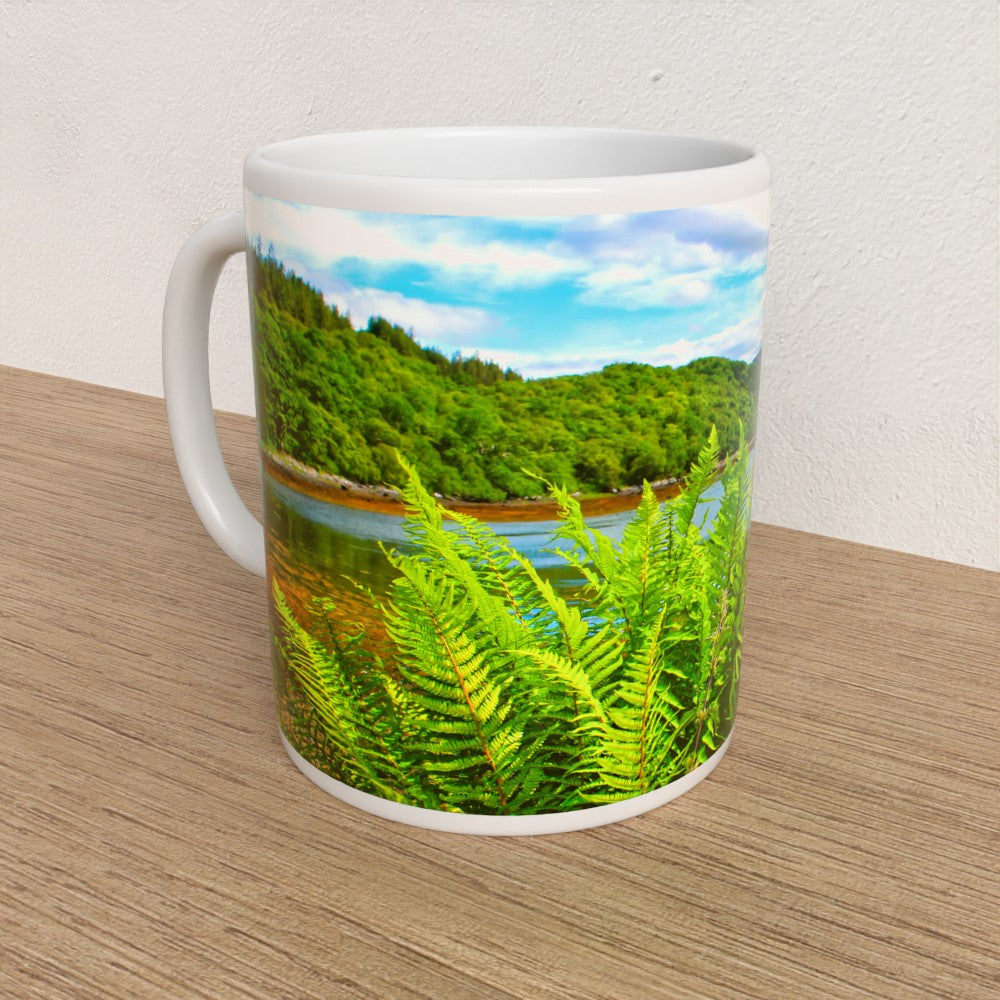 Mug with a scenic design of a lake and trees on a wooden surface