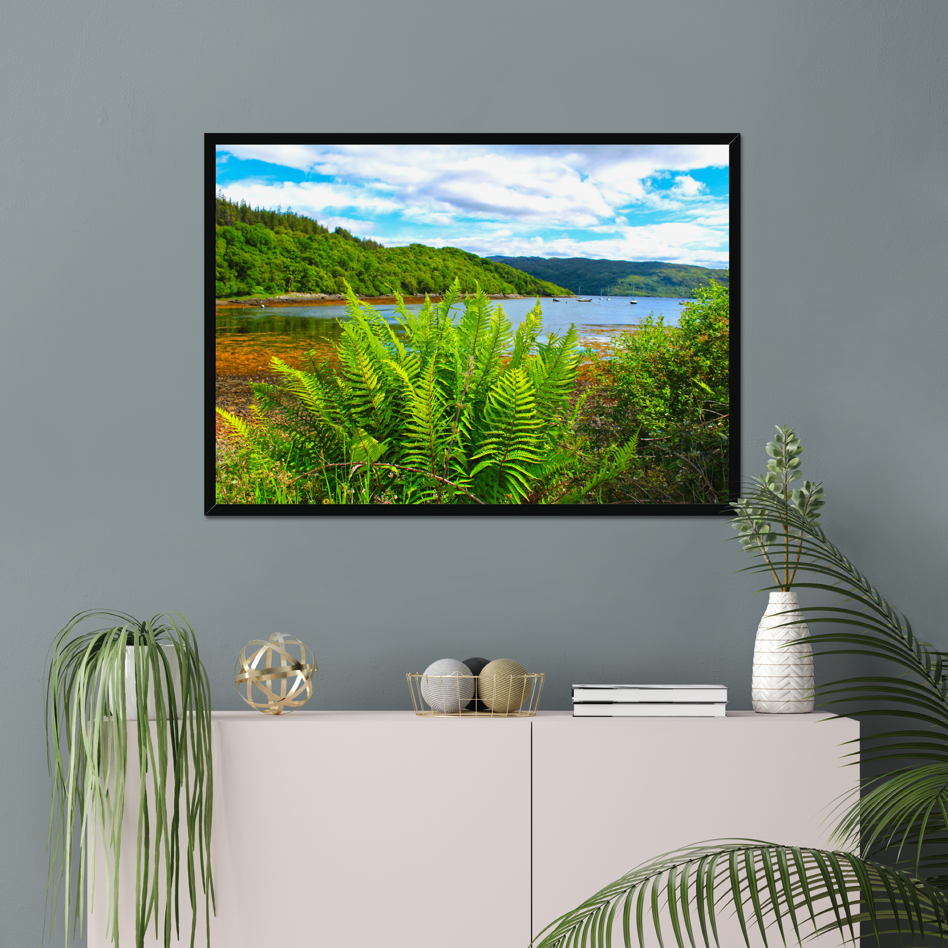 Framed photograph of a scenic landscape with a lake and forest, displayed on a wall above a cabinet.