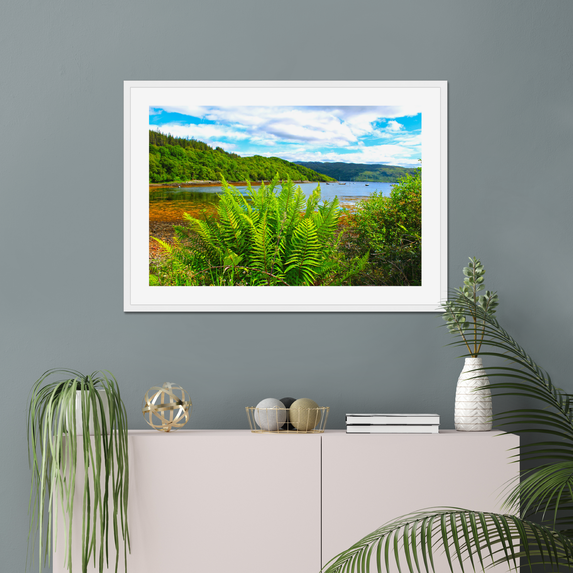 Framed photograph of a scenic landscape with a lake and forest, displayed on a wall above a cabinet.