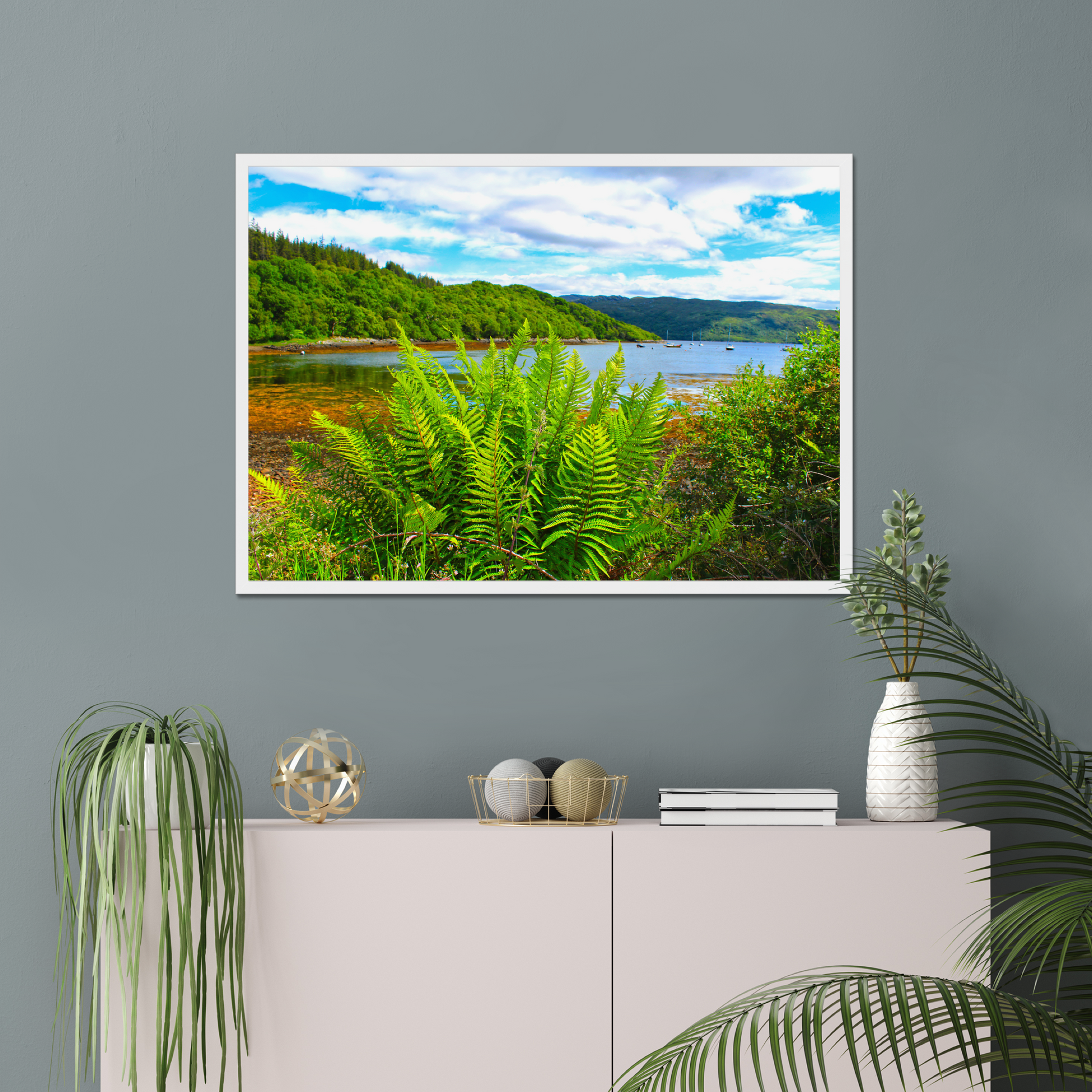 Framed photograph of a scenic landscape with a lake and forest, displayed on a wall above a cabinet.