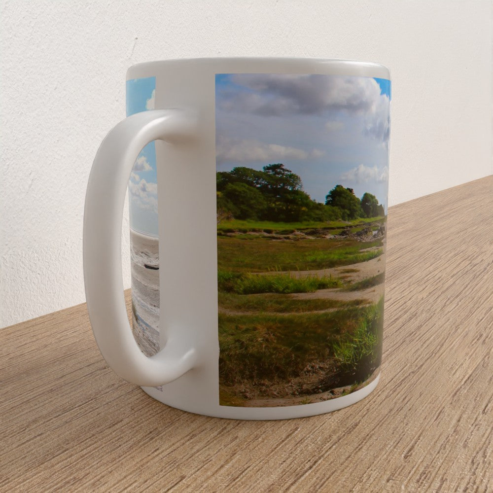 White mug with a scenic print of a field and trees on a wooden surface