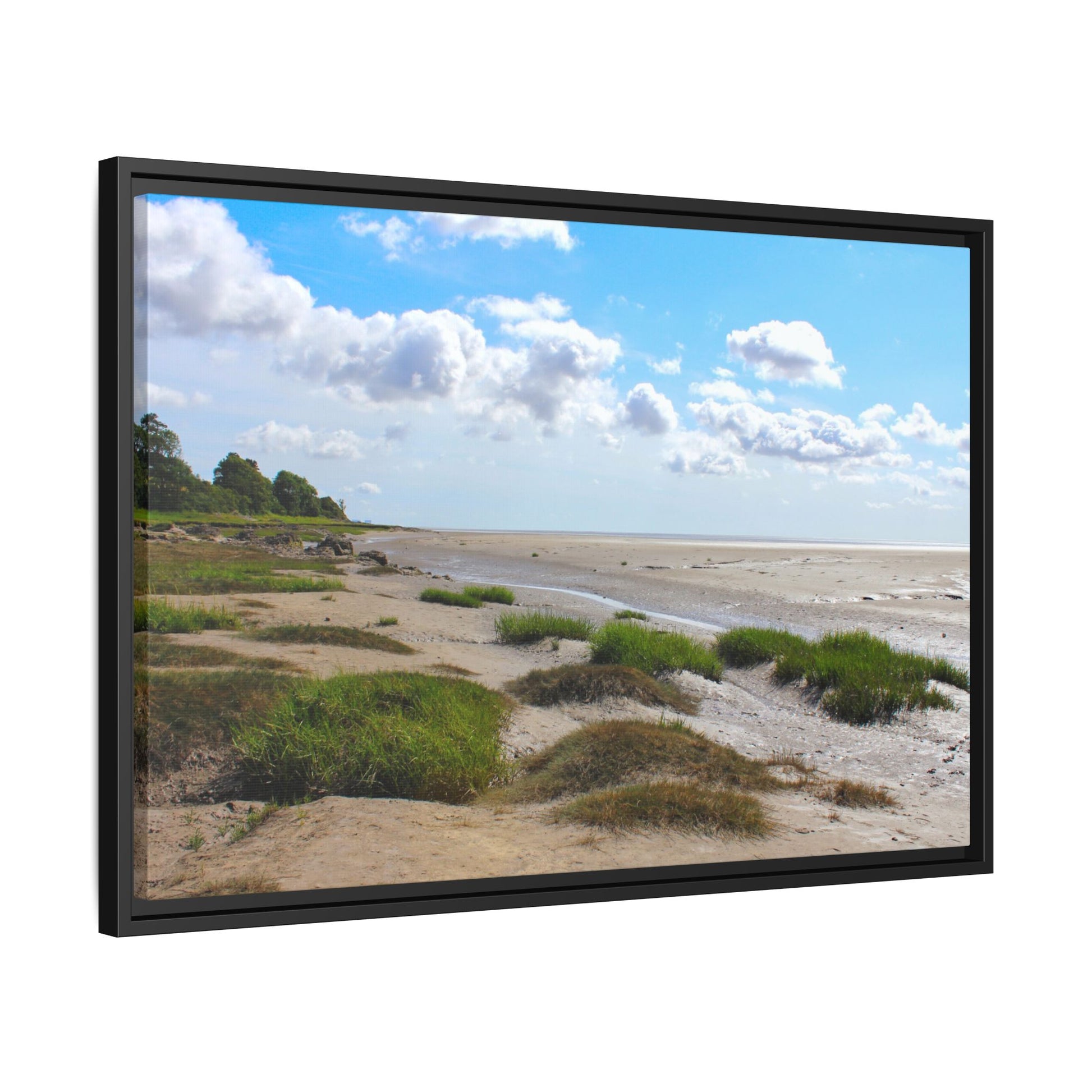Beach scene with sand, grass, and a blue sky with clouds, framed in black.