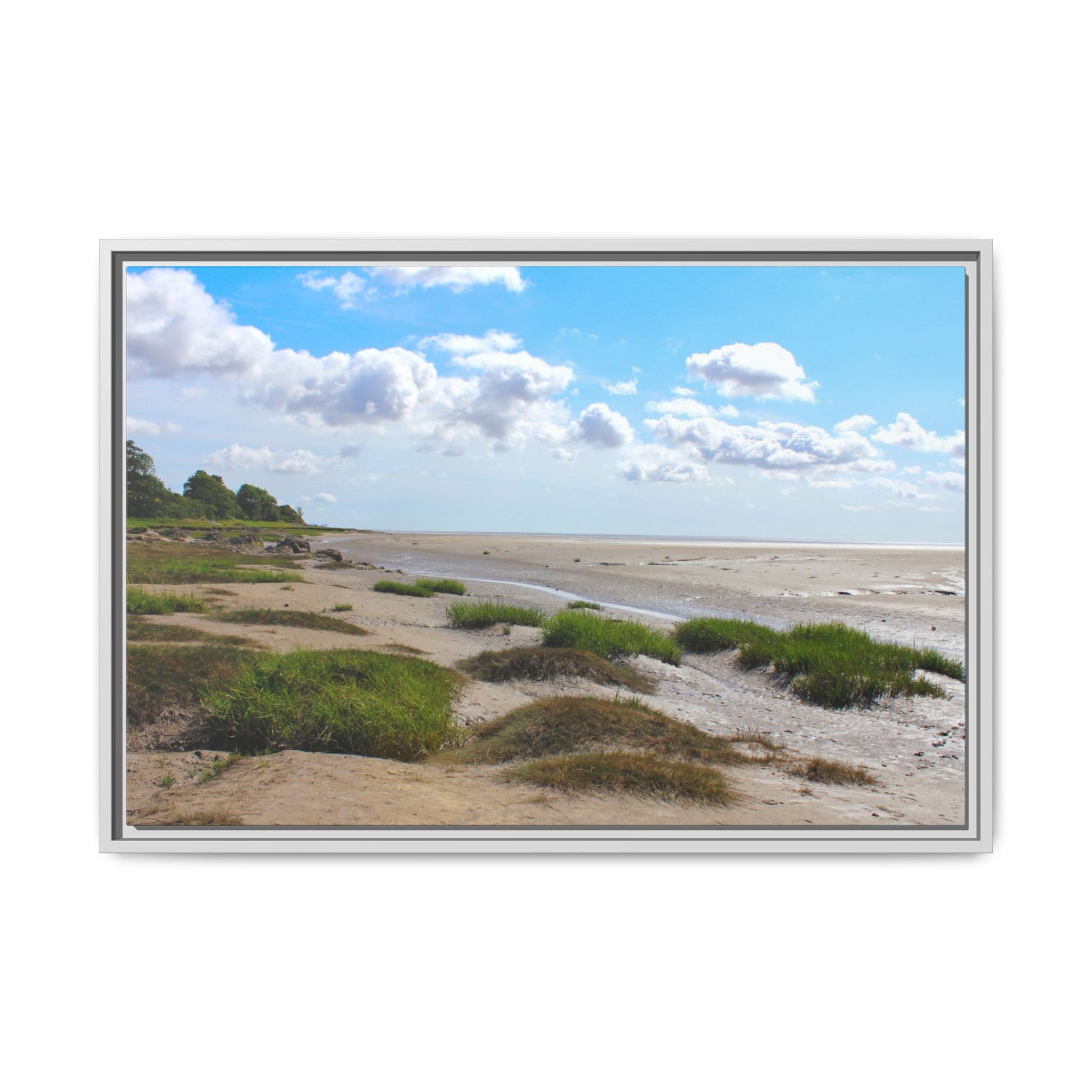 Framed photograph of a coastal landscape with sand, grass, and a blue sky.