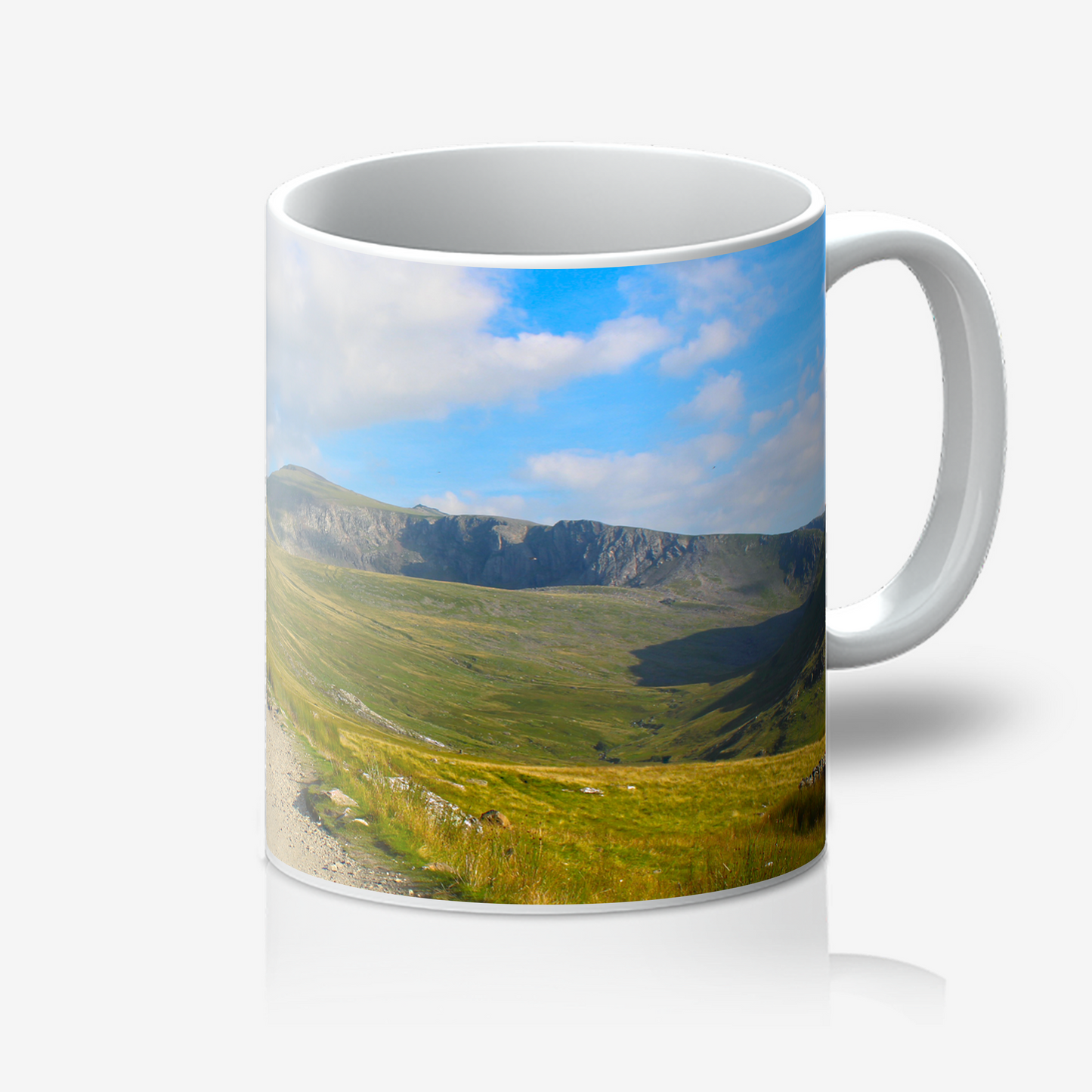 Mug with a scenic landscape of mountains and fields printed on it.