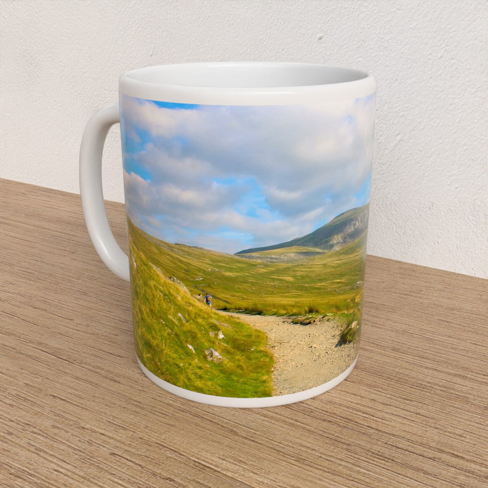 Mug with a scenic design of a mountain landscape on a wooden surface.