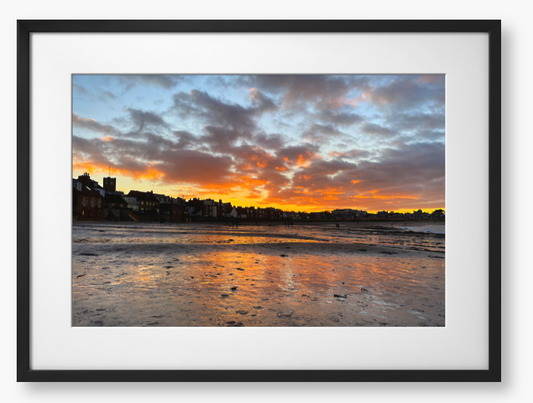 Framed Photo of a sunset over a coastal town with vibrant colours reflected in the water.