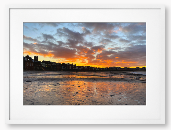 Framed Photo of a sunset over a coastal town with vibrant colours reflected in the water.