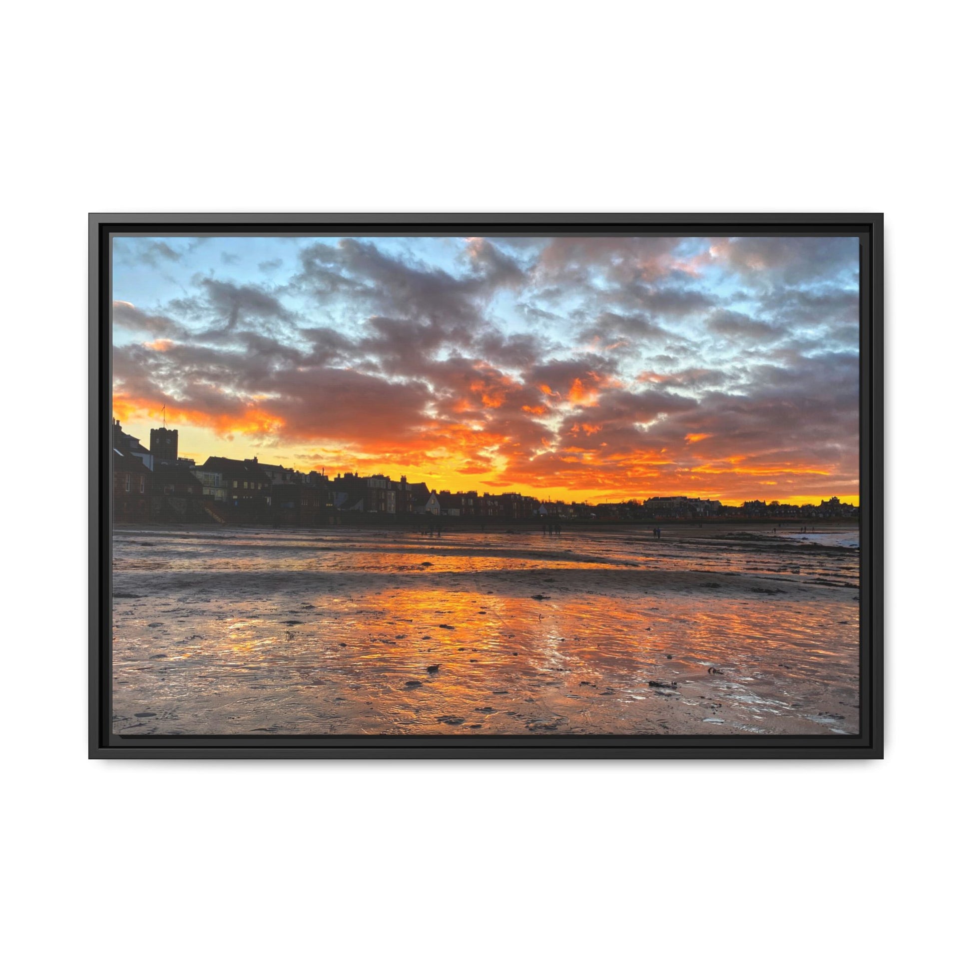 Framed artwork of a sunset over a coastal town with vibrant colors.
