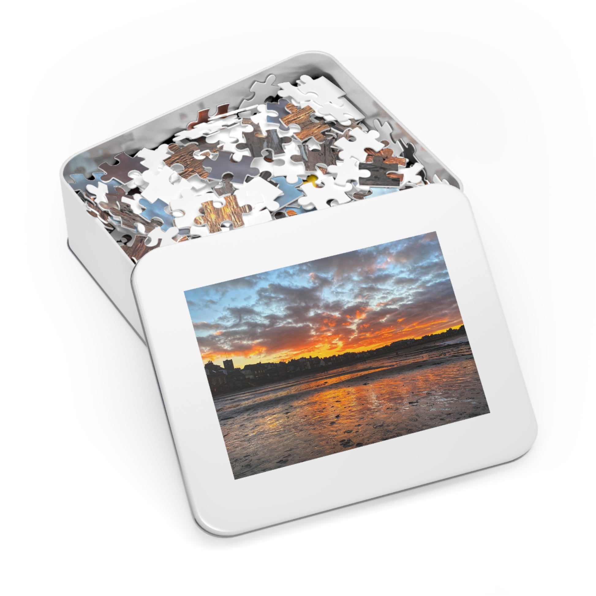 Jigsaw puzzle in a tin with a sunset over water image on the lid