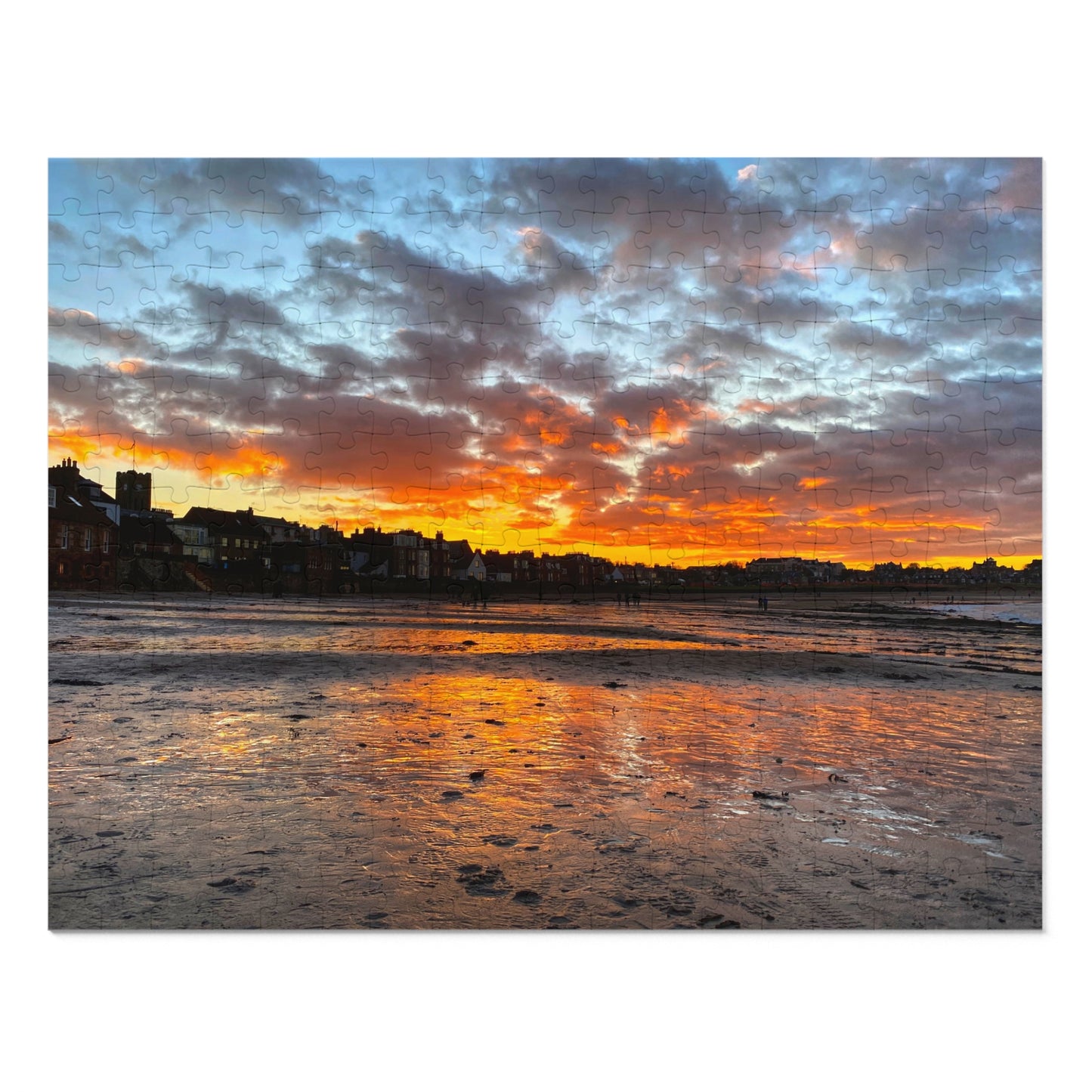 Sunset over a coastal town with colorful clouds reflecting on the water.