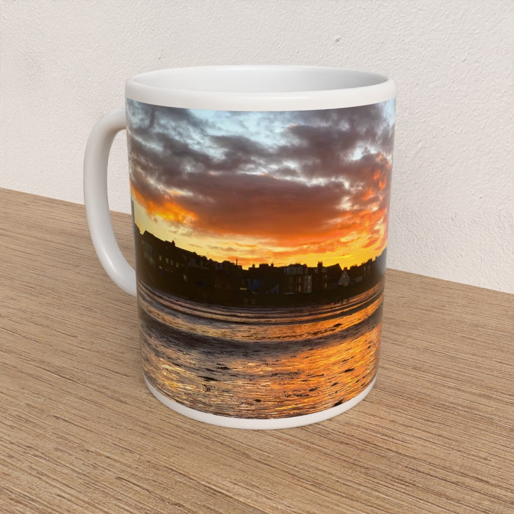 Mug with a sunset over water design on a wooden surface
